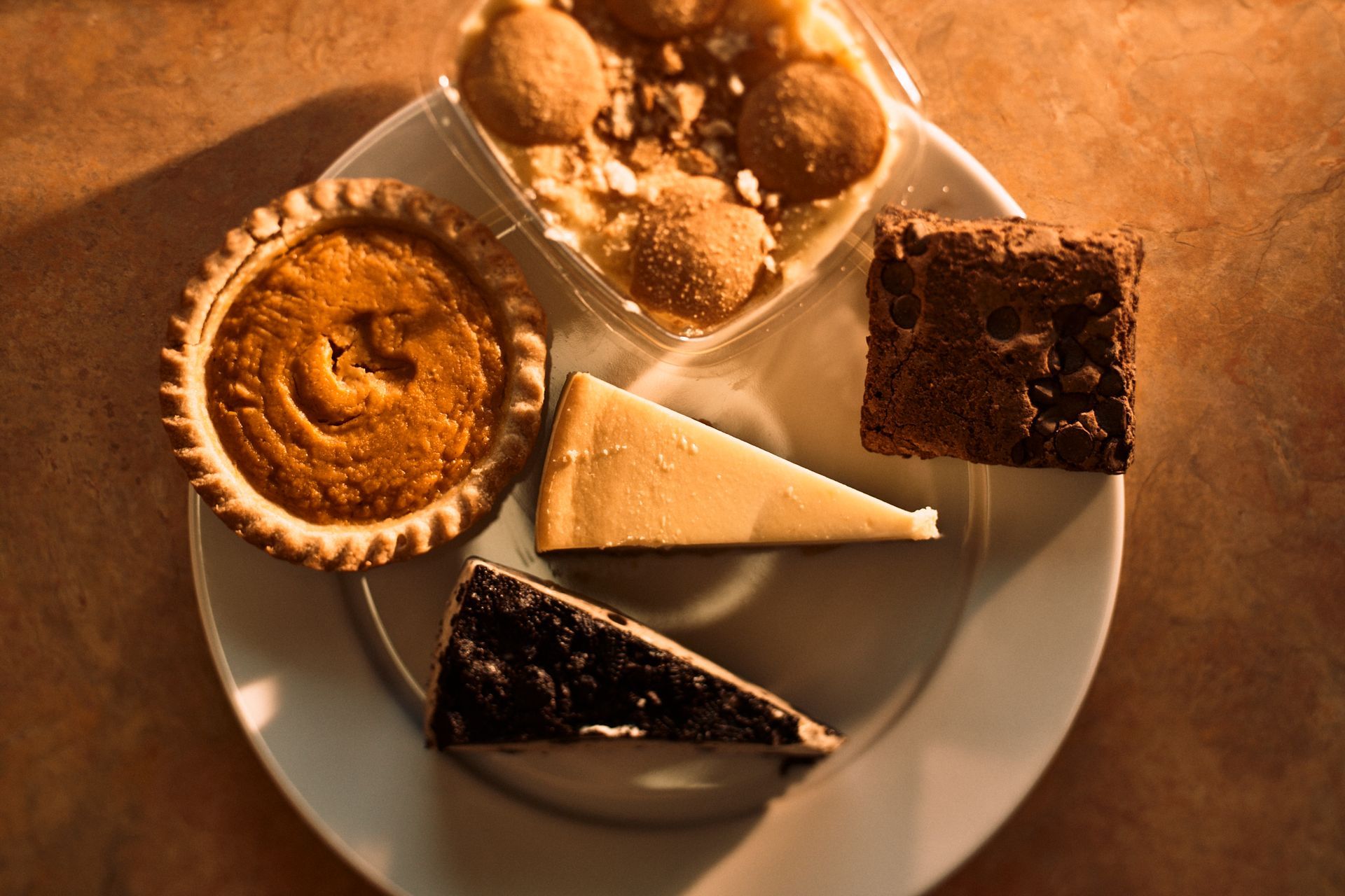 A plate of desserts including a pumpkin pie and a brownie