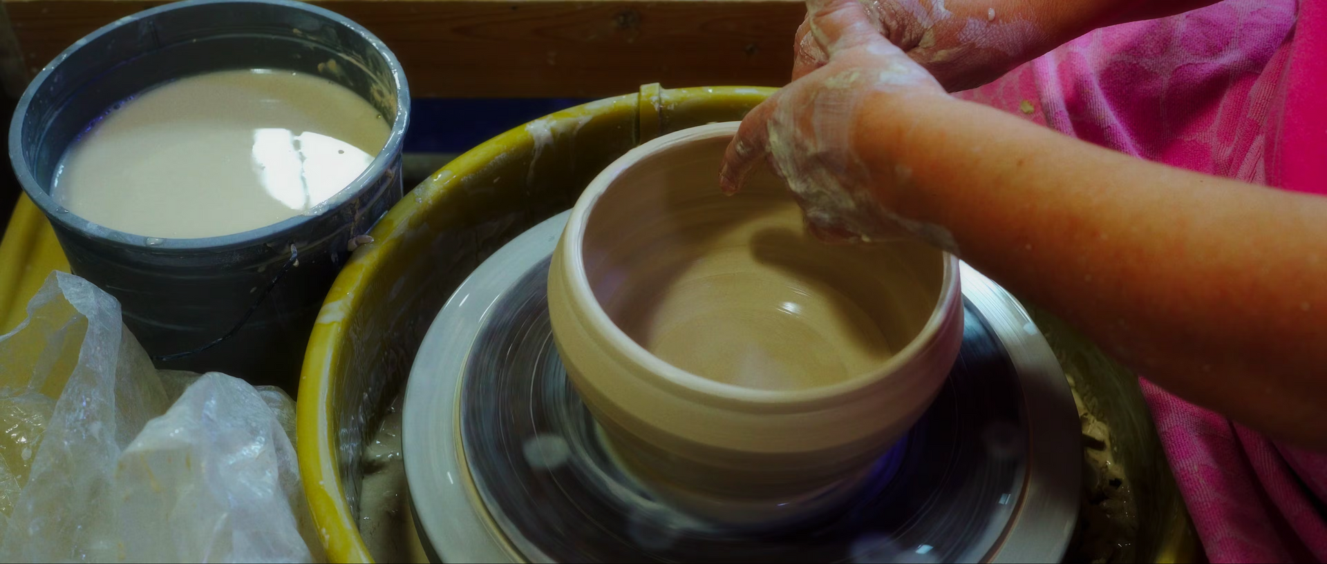 A person is making a bowl on a pottery wheel.