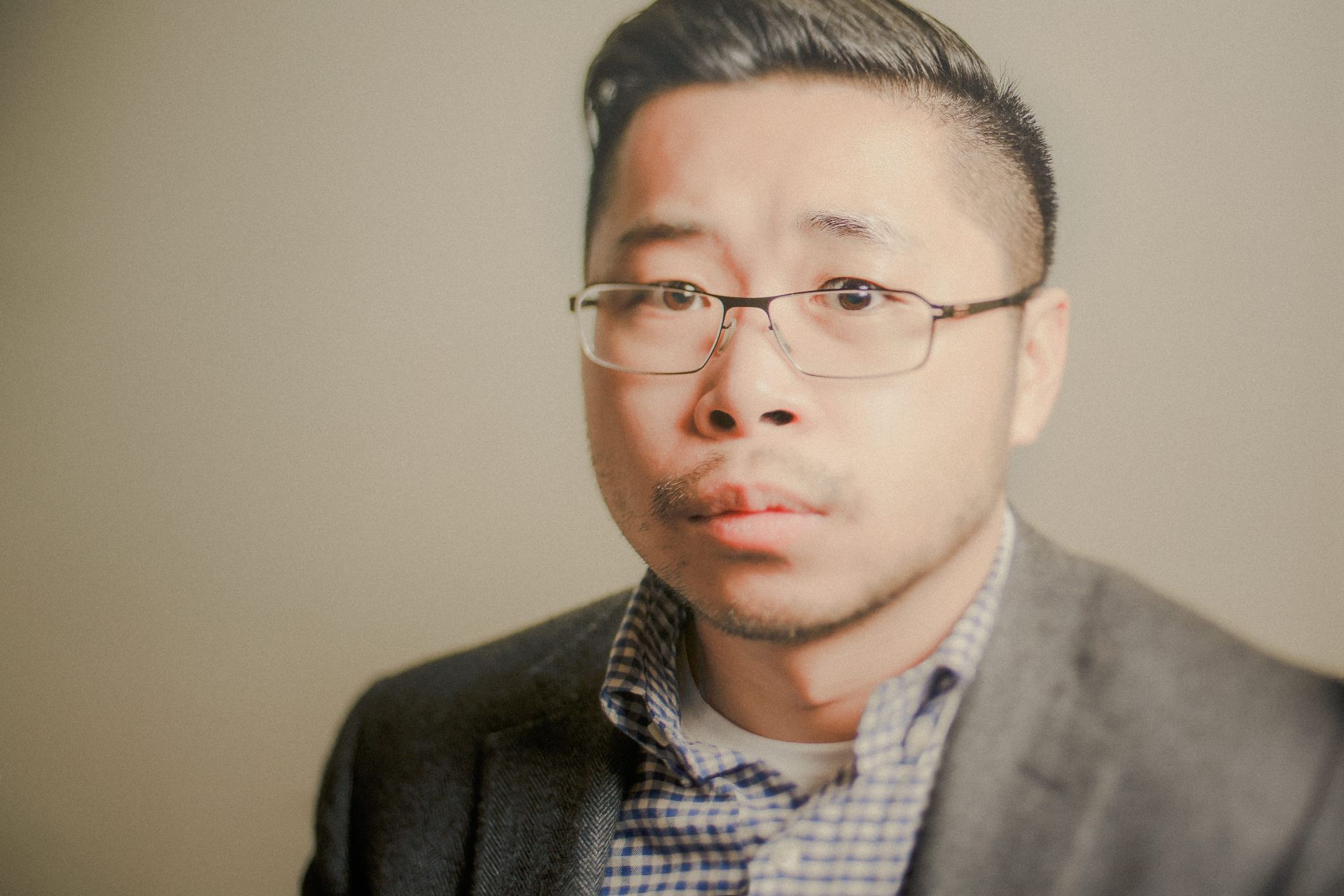 A man wearing glasses and a suit is looking at the camera.