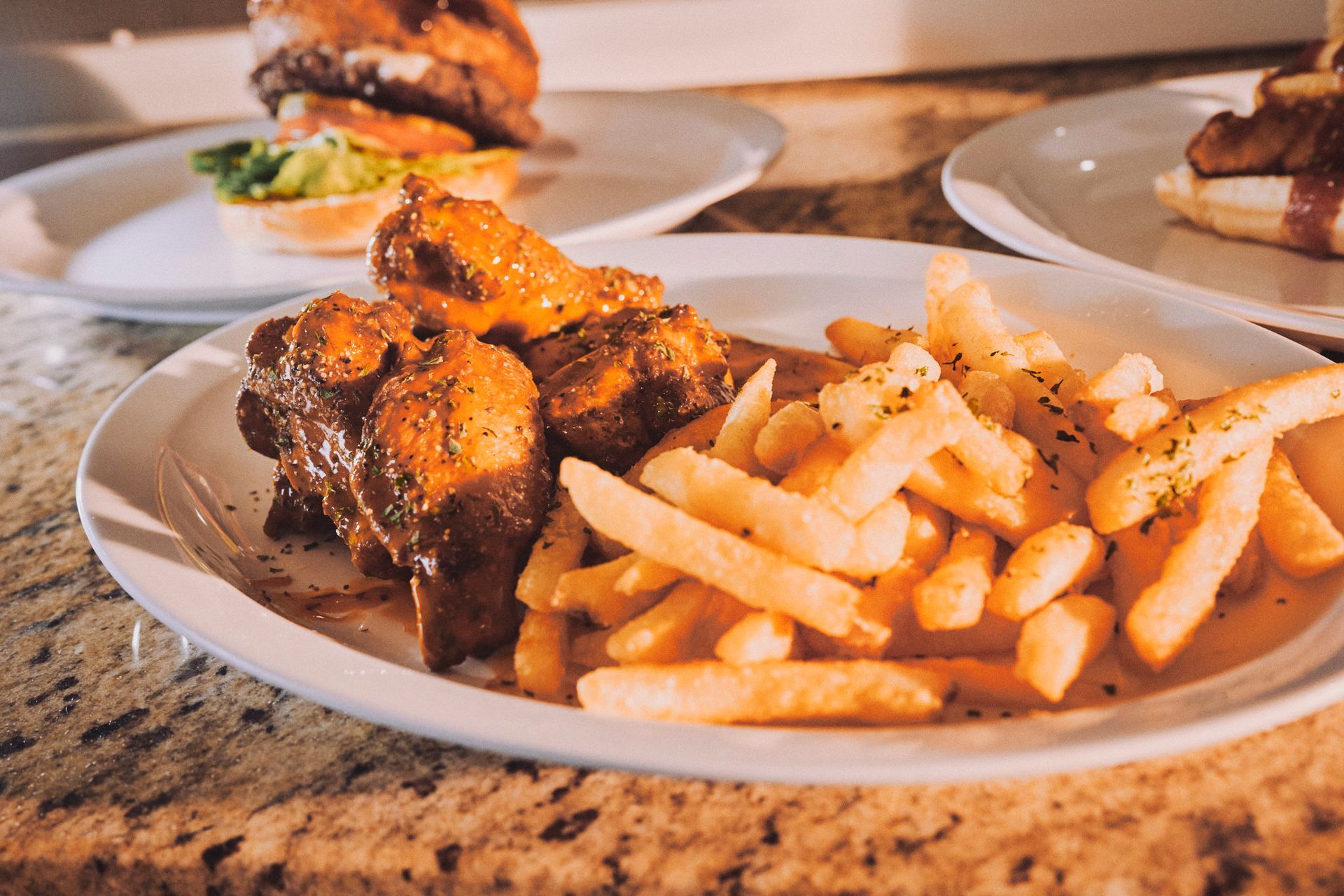 A plate of chicken wings and french fries on a table.