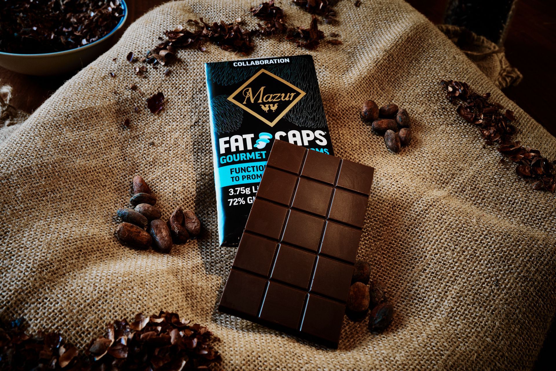 Chocolate bar and box on burlap with cocoa beans.