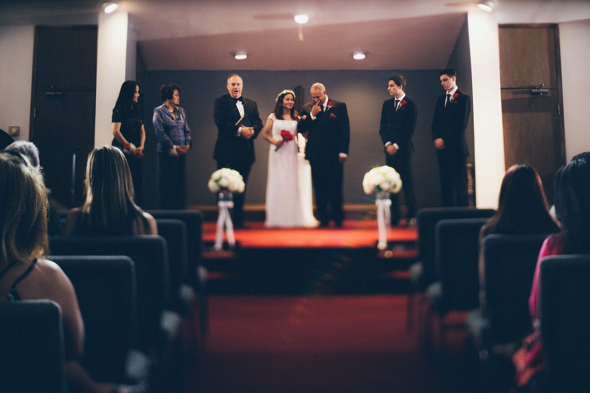 Wedding ceremony in a chapel with the bride, groom, and wedding party standing at the altar.