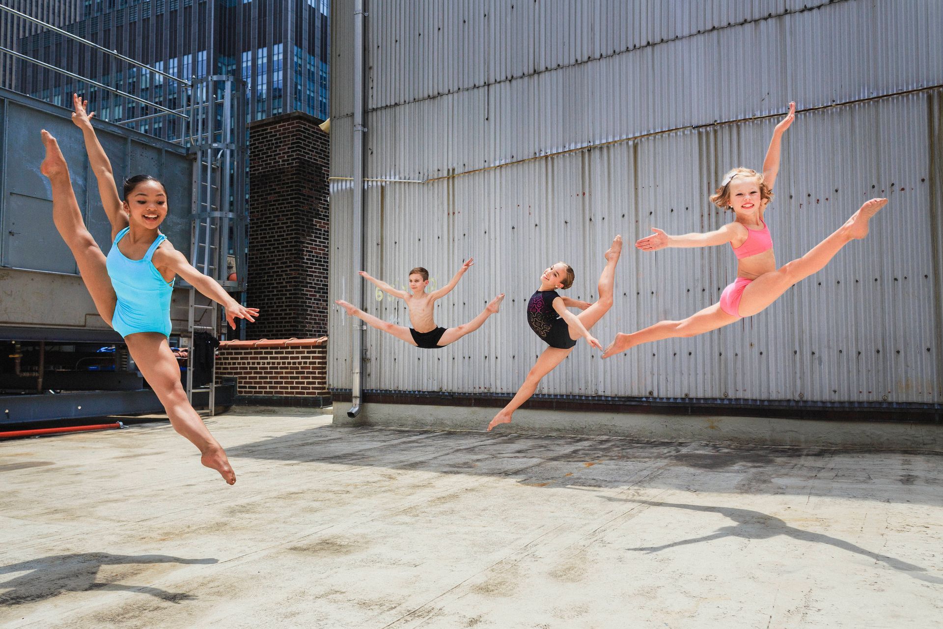 A group of young girls are jumping in the air in front of a building.