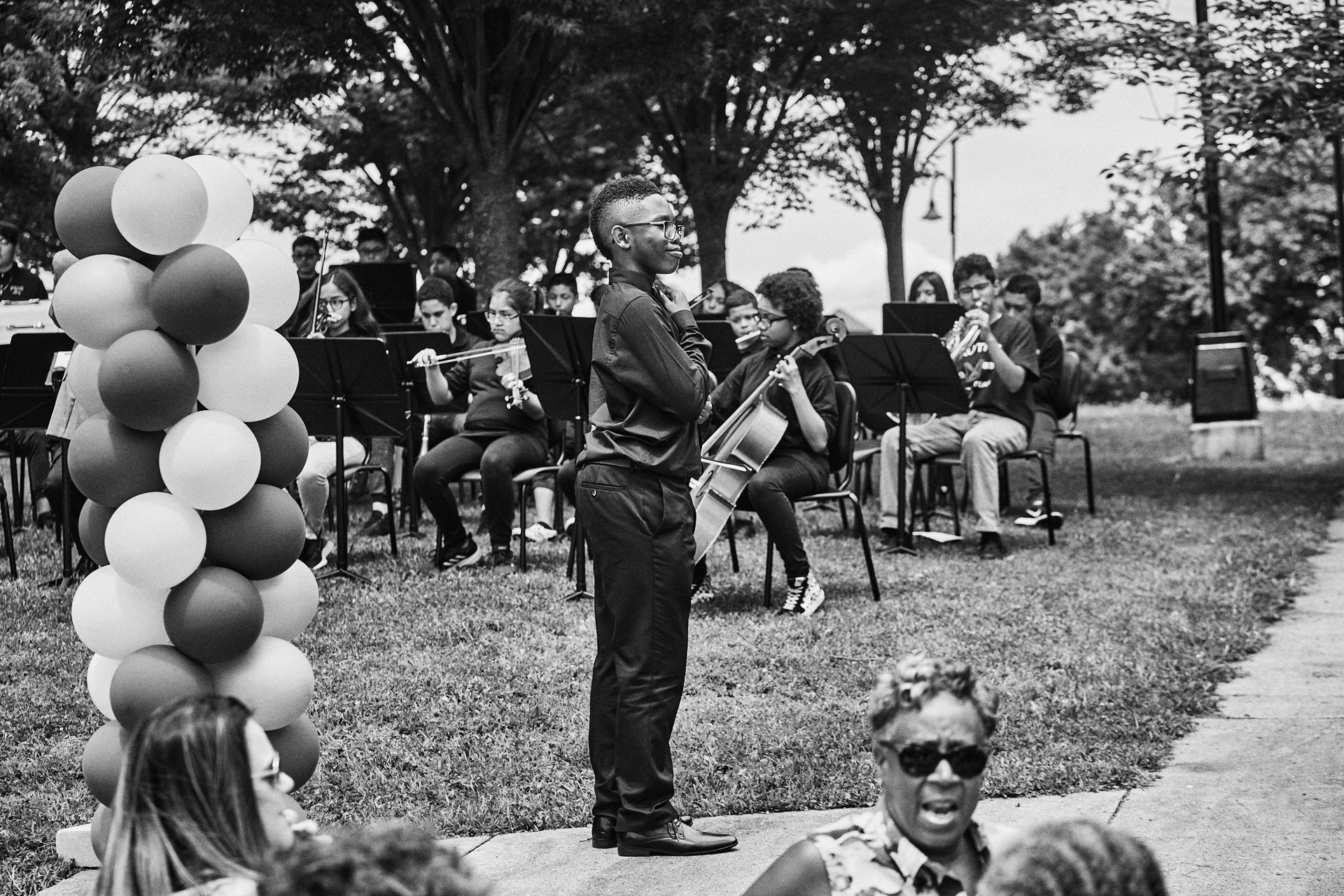 A black and white photo of a man standing in front of an orchestra.