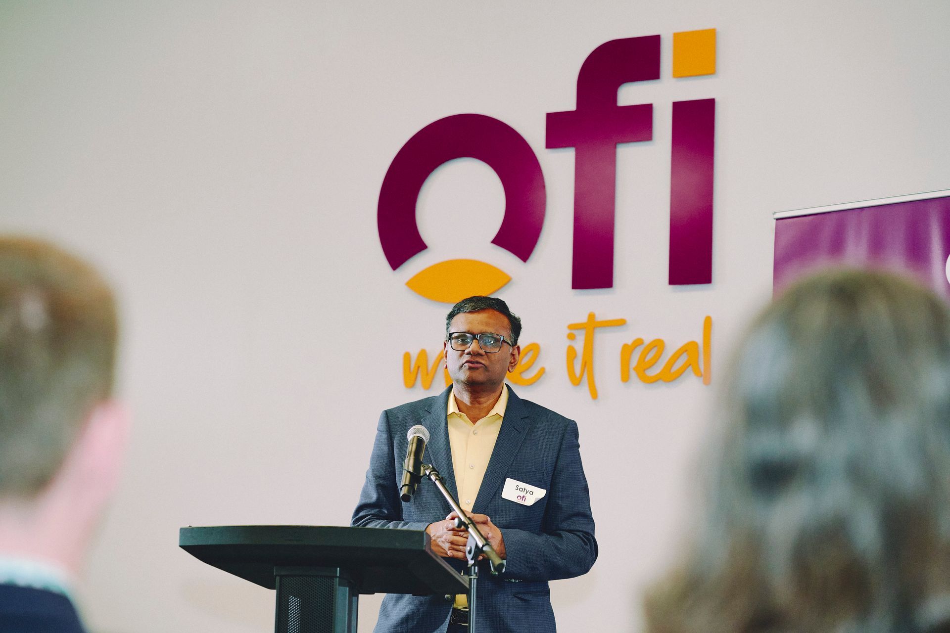 Man speaking at a podium in front of a company logo.