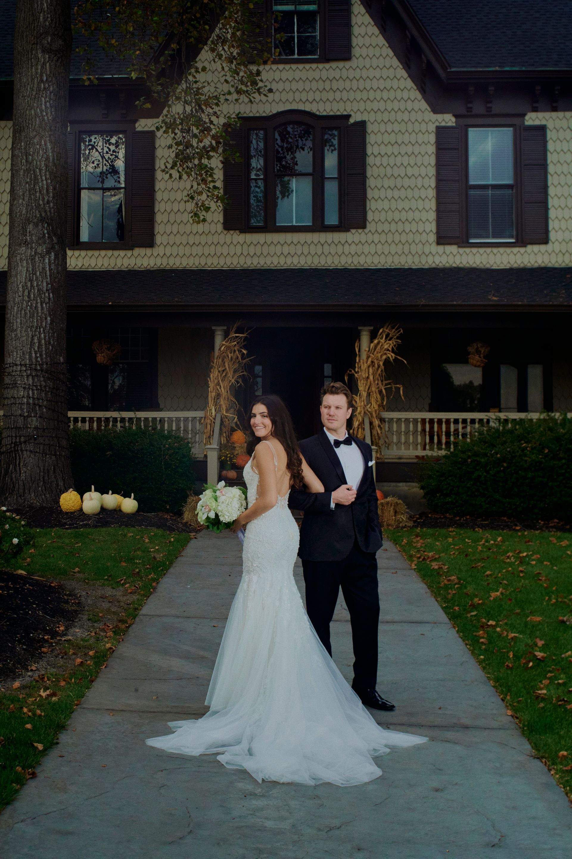 Bride in wedding dress smiles, looks at camera in limo. Man in suit holds phone.