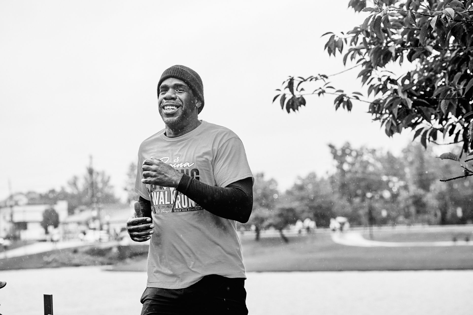 A black and white photo of a man running in a park.
