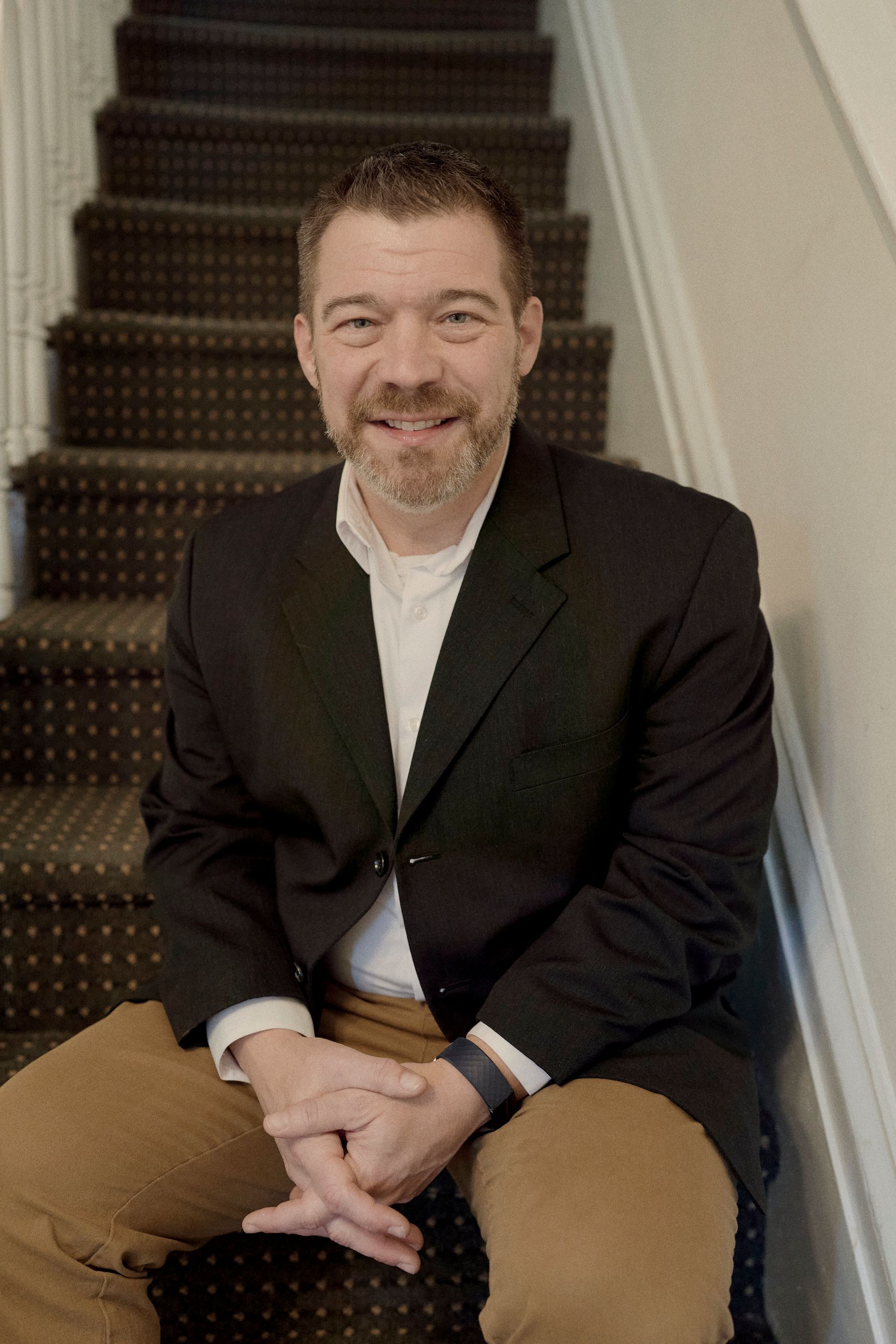 A man in a suit is sitting on a set of stairs.