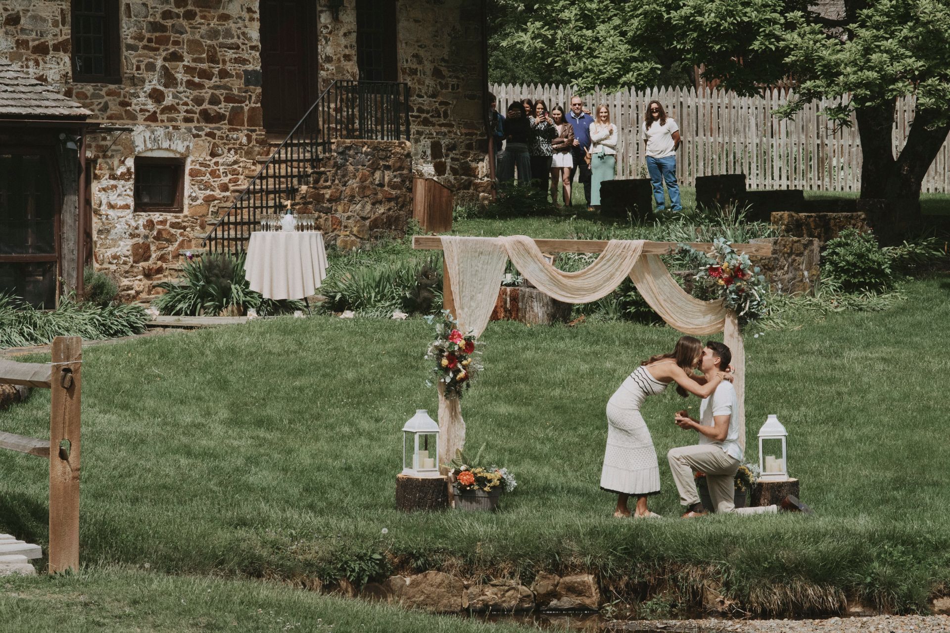 A man is proposing to a woman in front of a stone building.