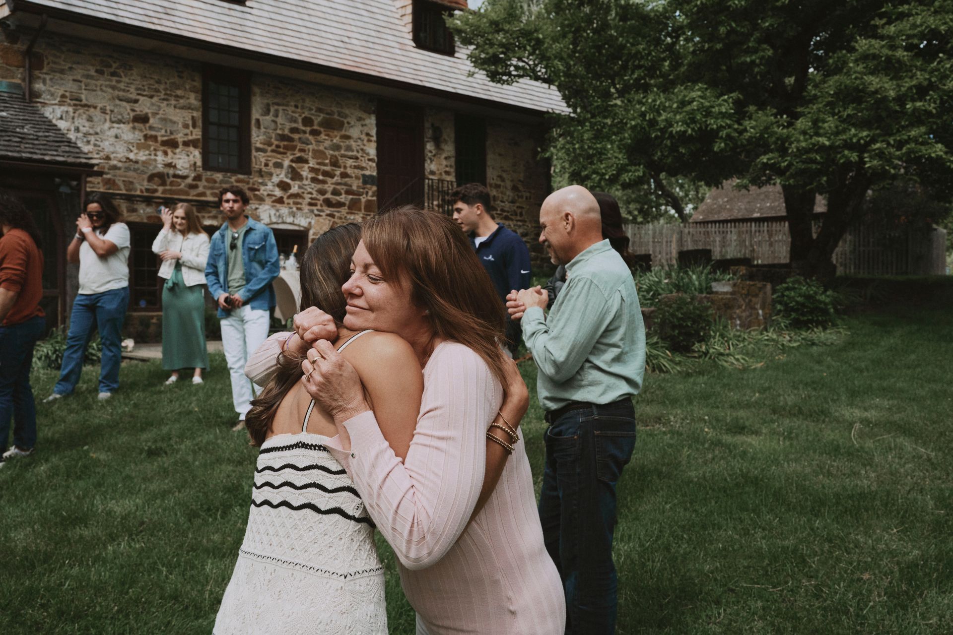 A woman is hugging another woman in front of a group of people.