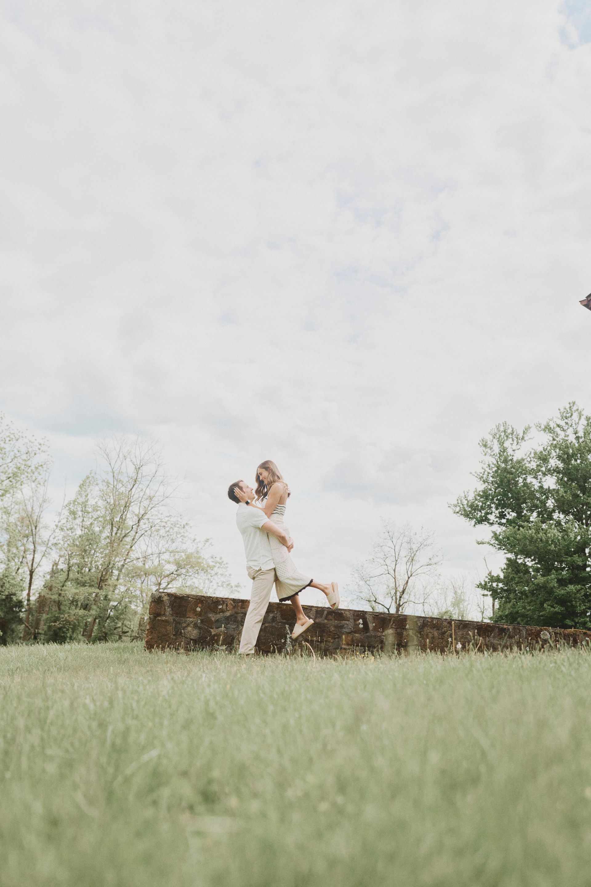 A man is holding a woman in his arms in a field.