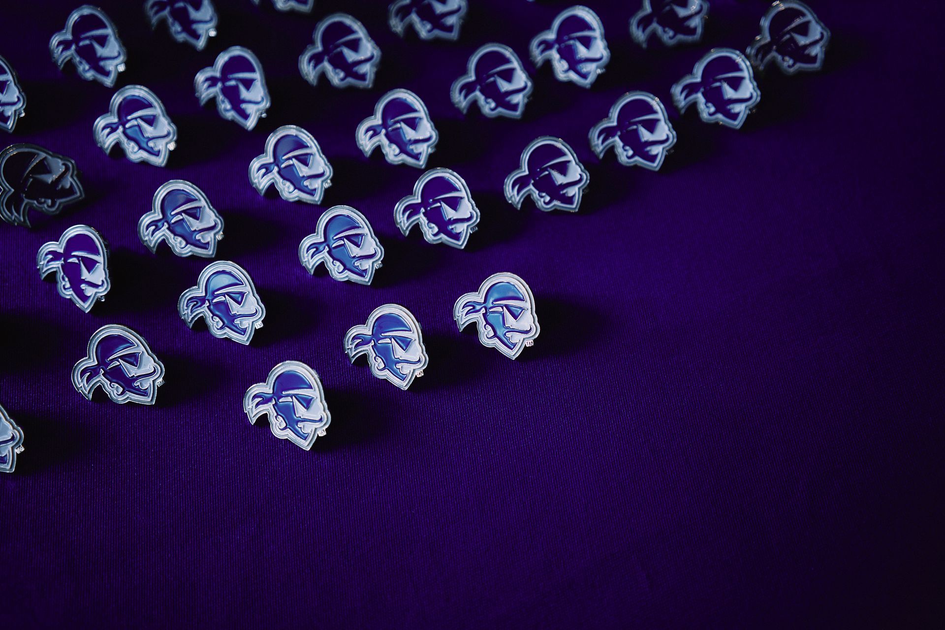 Blue pins in a repeating pattern of a character's face on a purple textured background.