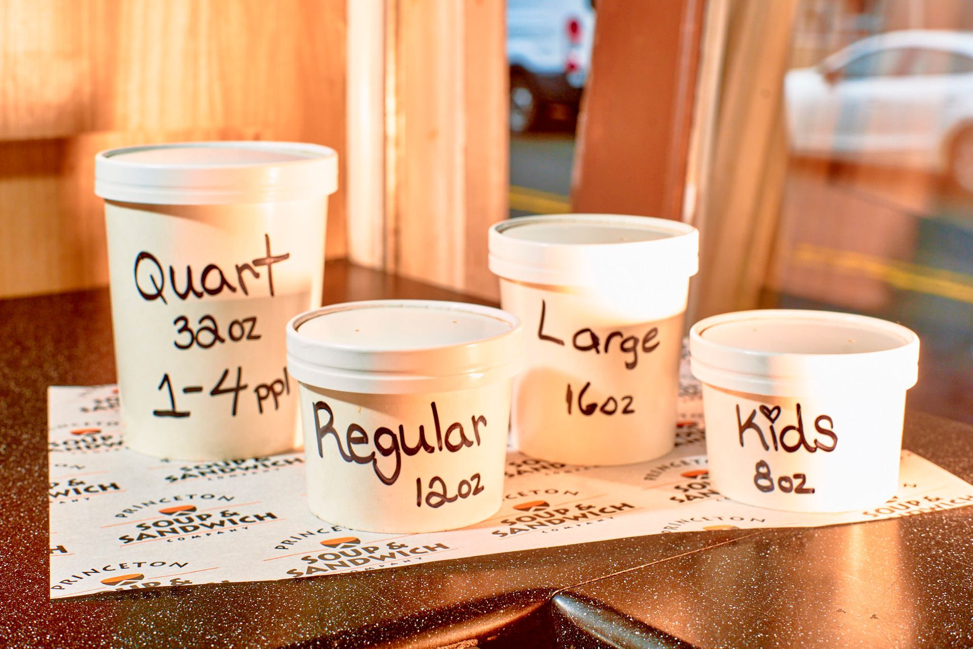 Four containers of ice cream sizes: Quart, Large, Regular, and Kids, on a counter.