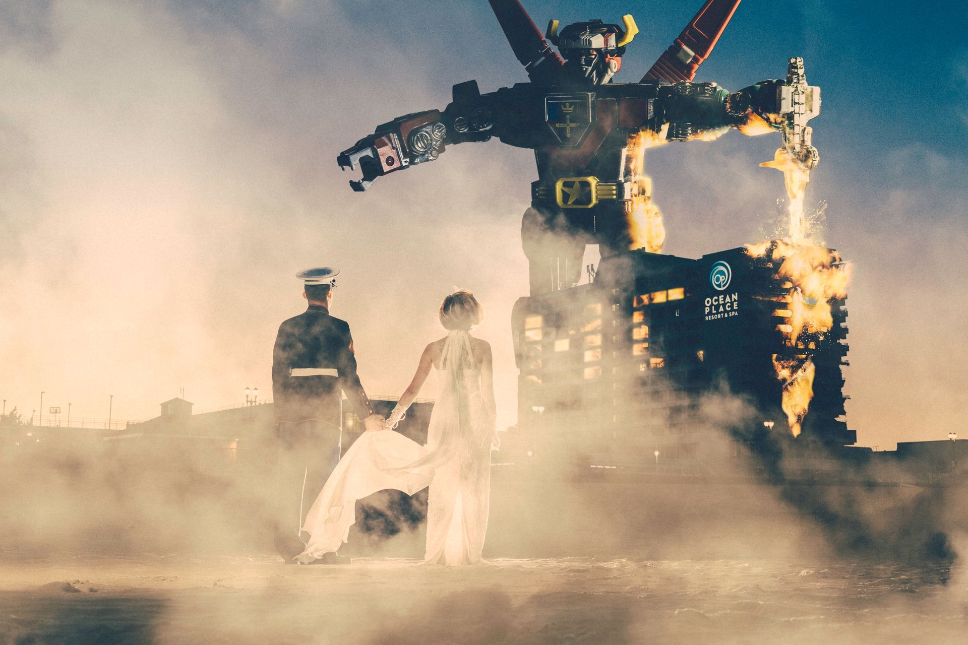 Giant robot with fire blasts over two figures in a desolate landscape.