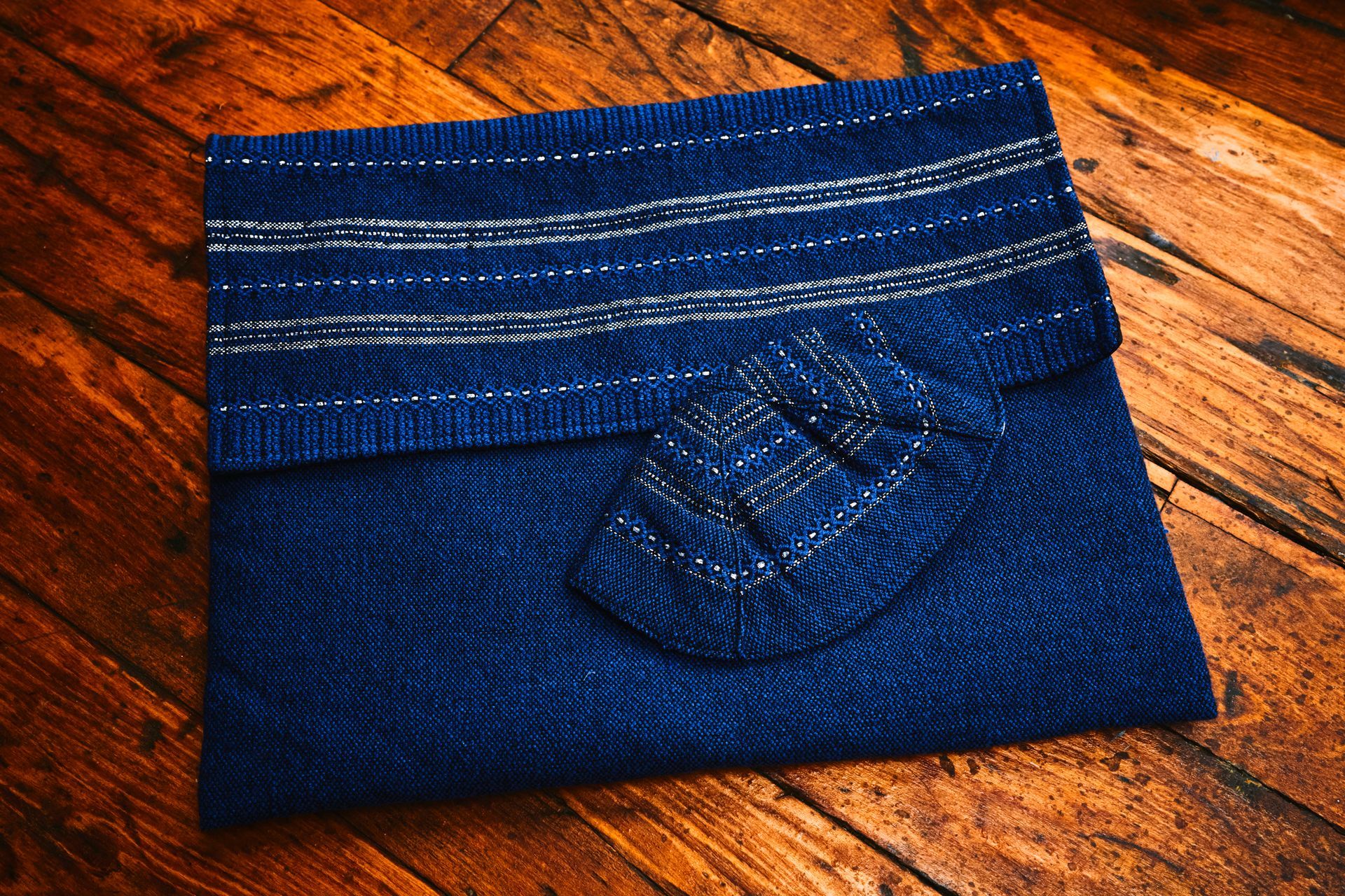 Blue beaded clutch bag on a wooden floor, featuring beaded detail on the flap.