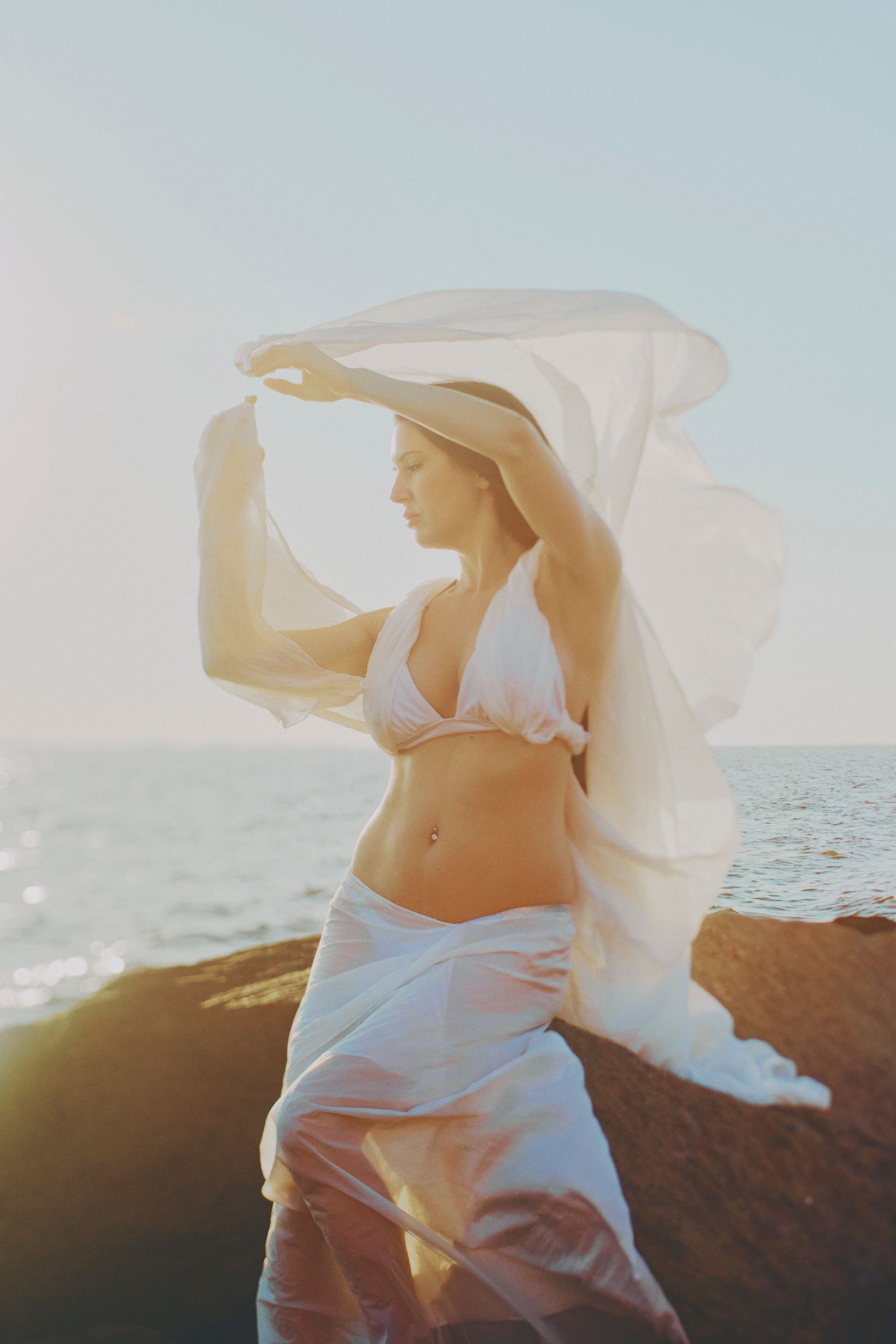 Woman in printed dress on outdoor stairs, looking upward.