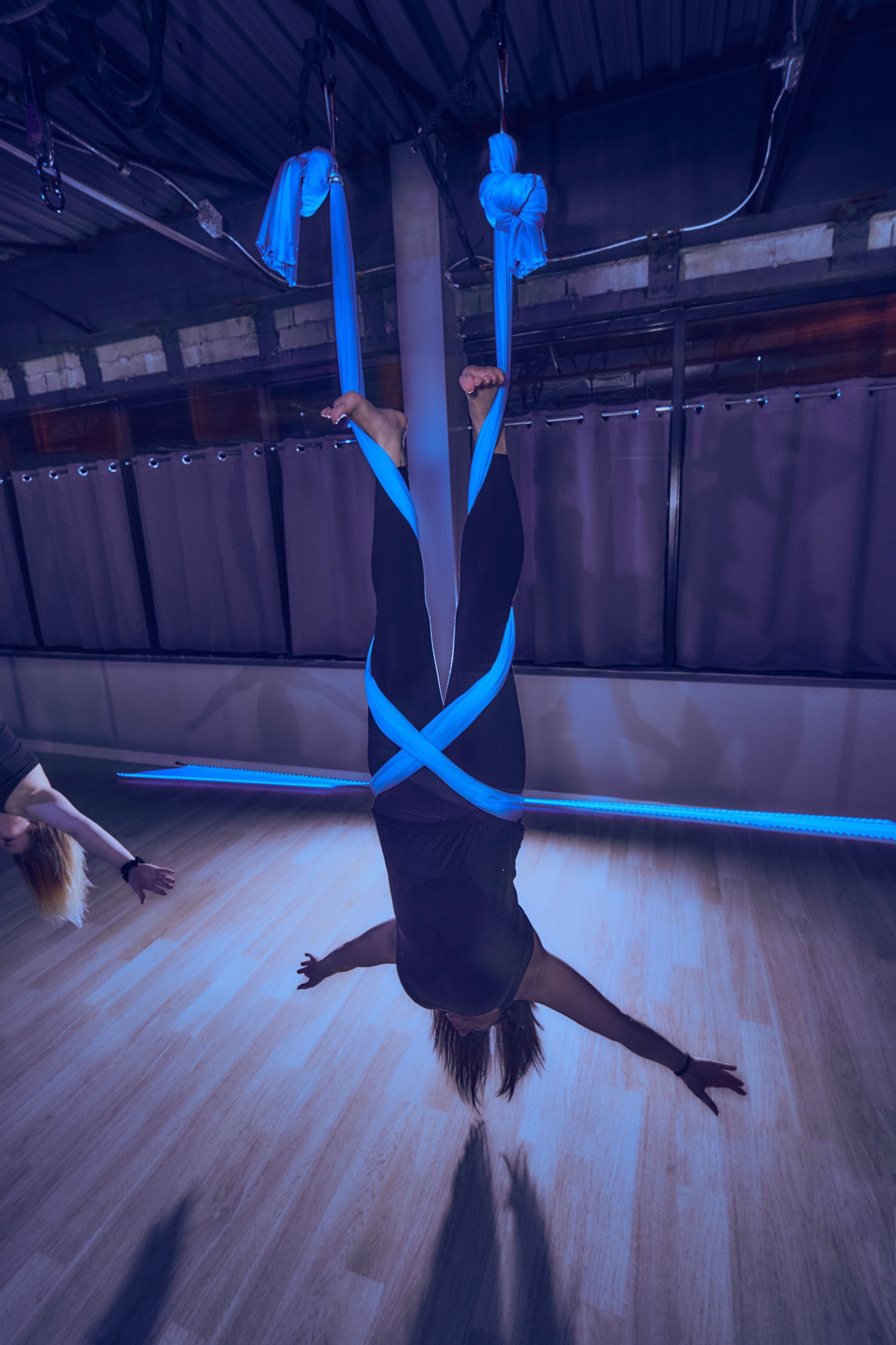 A woman is doing aerial yoga in a dark room