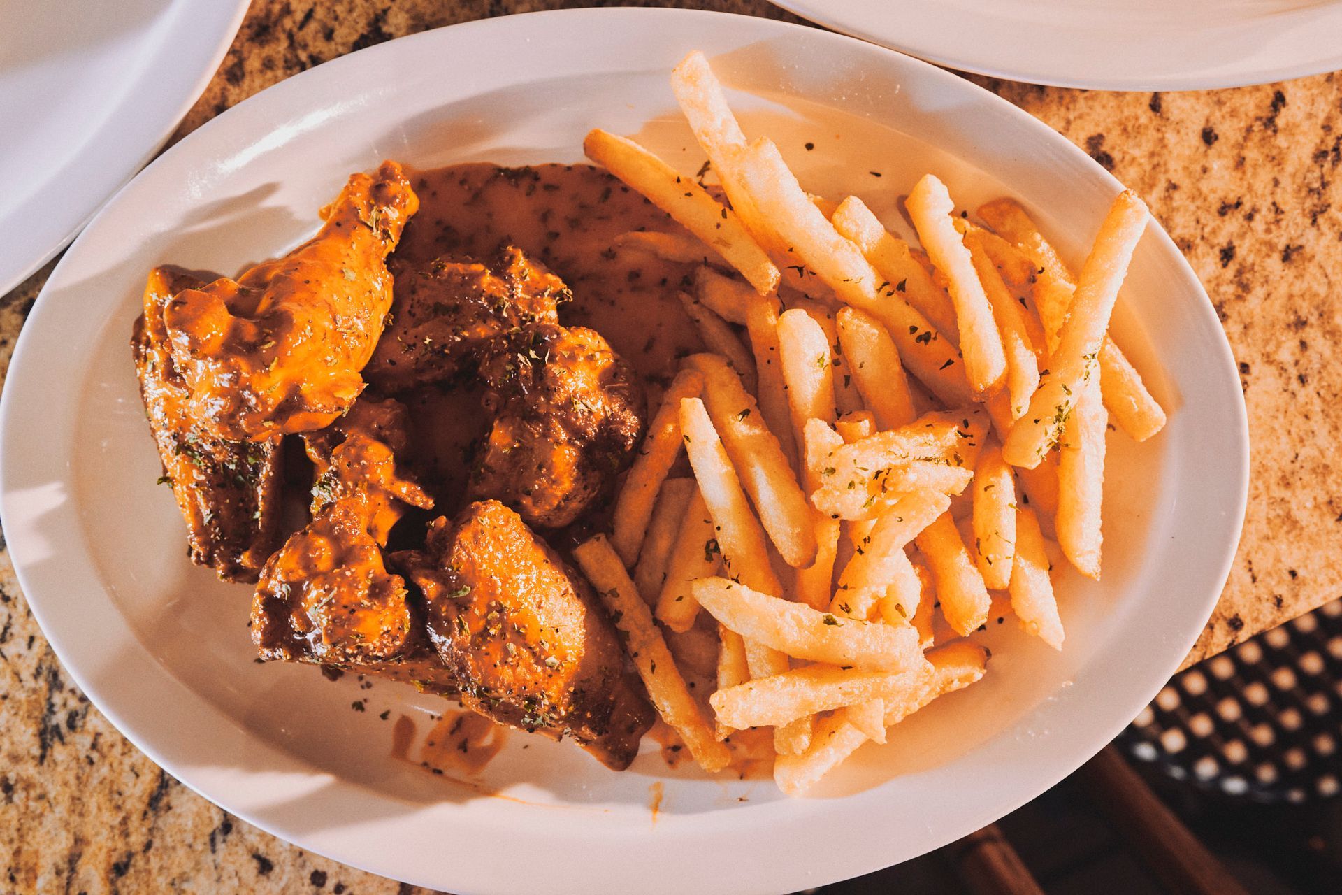 A white plate topped with chicken wings and french fries