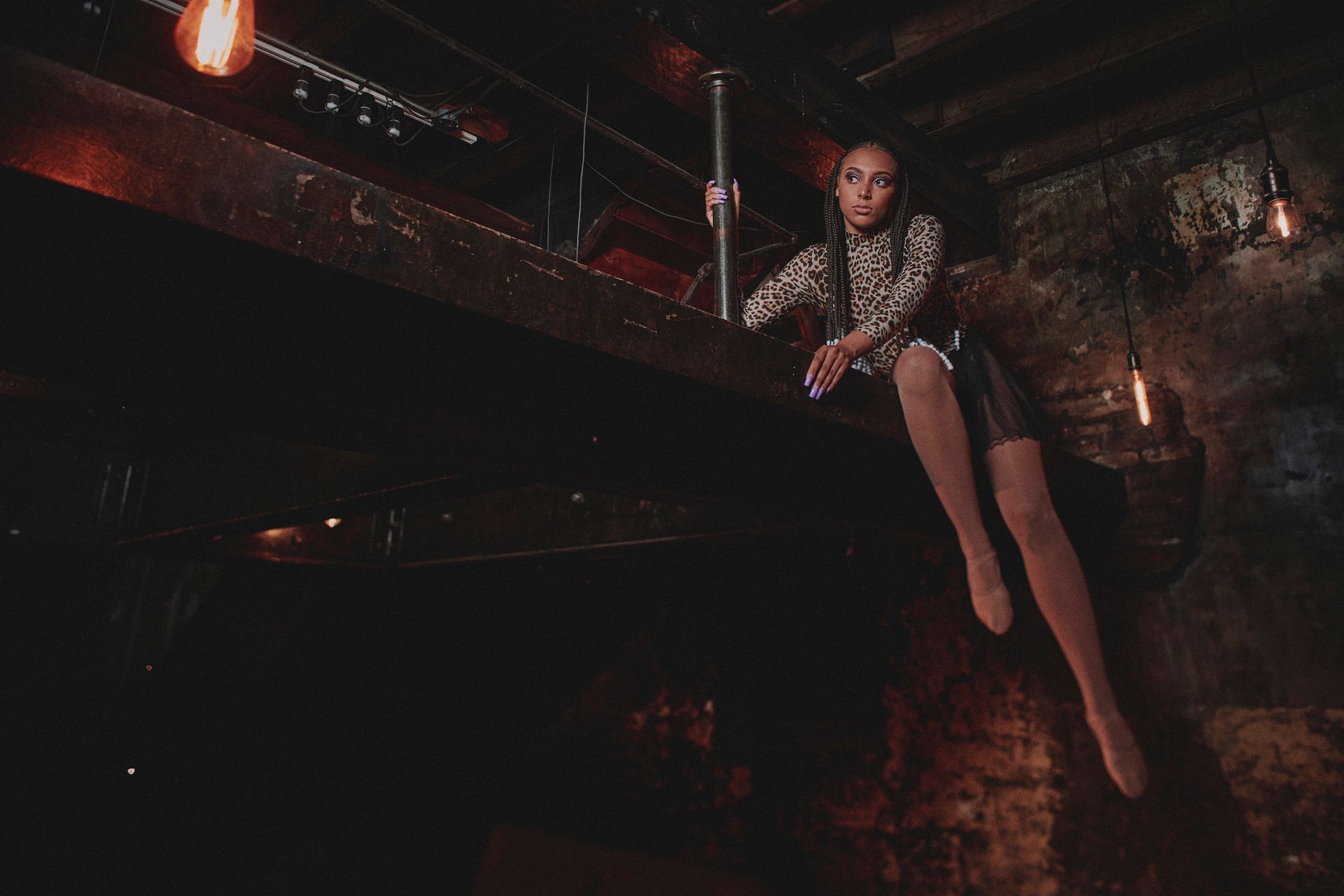 A woman is sitting on a pole in a dark room.