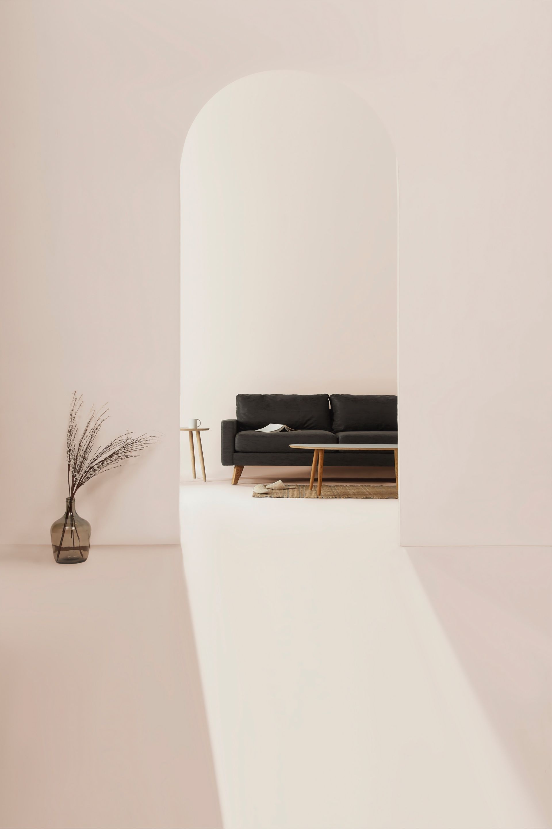 A living room with a black couch and a vase of flowers.