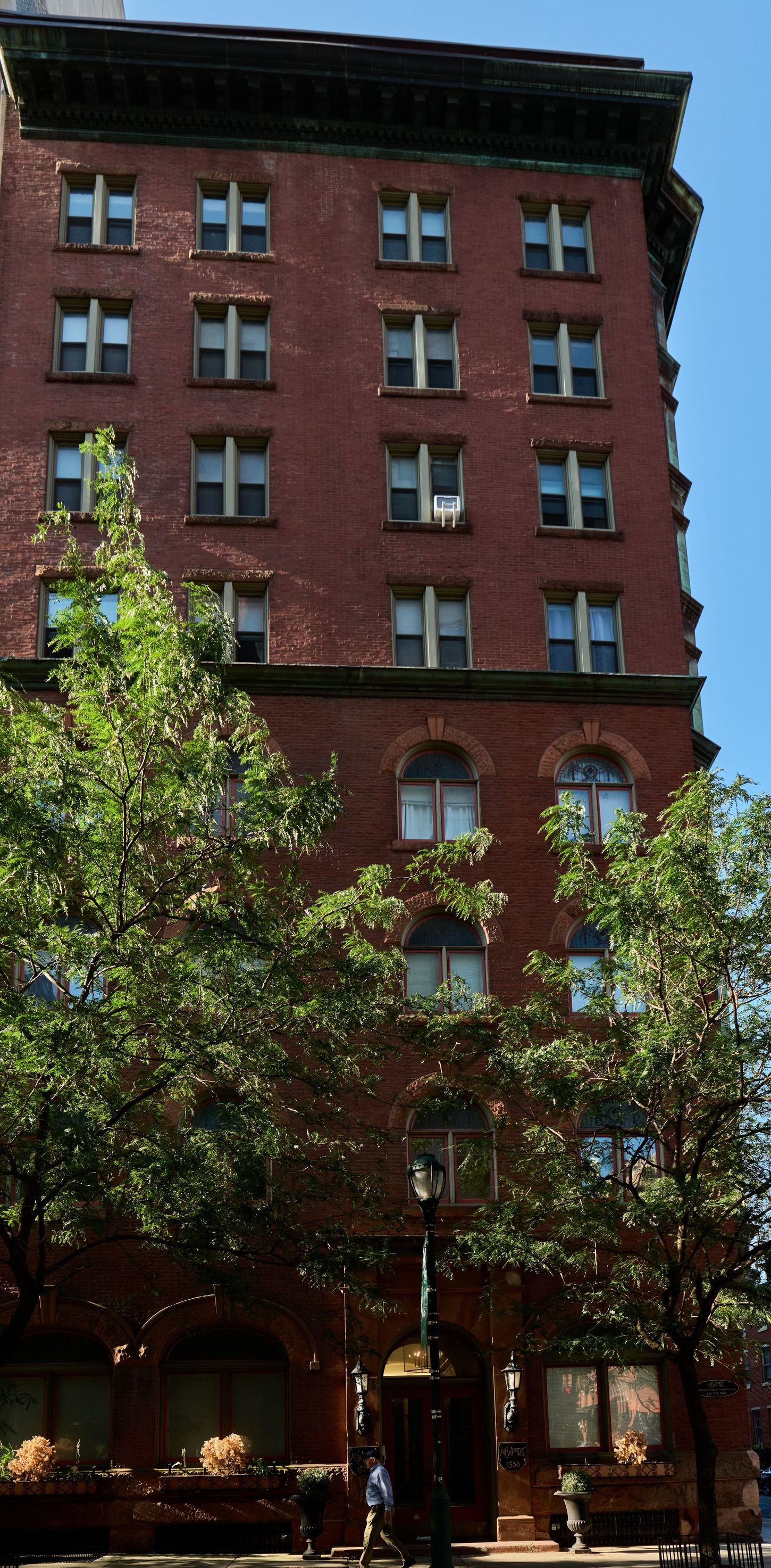 A large brick building with lots of windows and trees in front of it