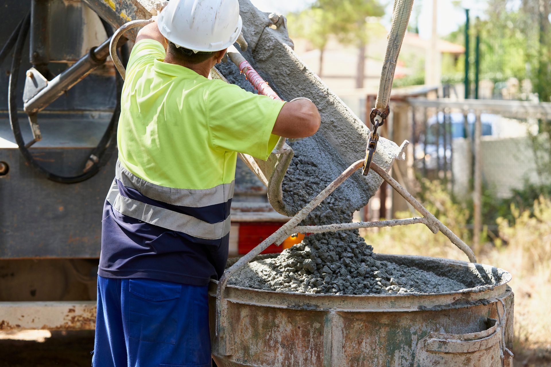 Construction worker pouring concrete from a truck into a metal container.