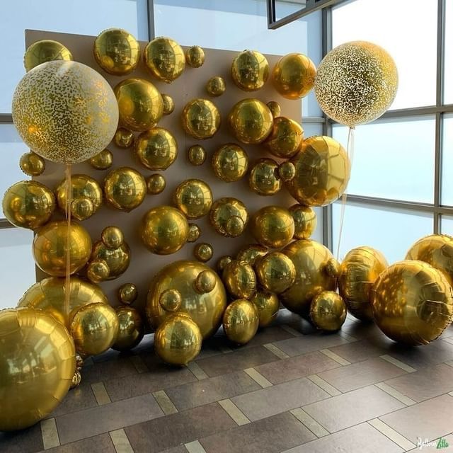 A bunch of gold balloons are sitting on a tiled floor