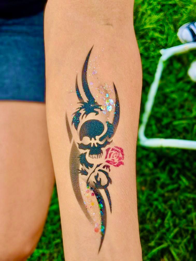 A person has a tattoo of a skull and a rose on their arm.