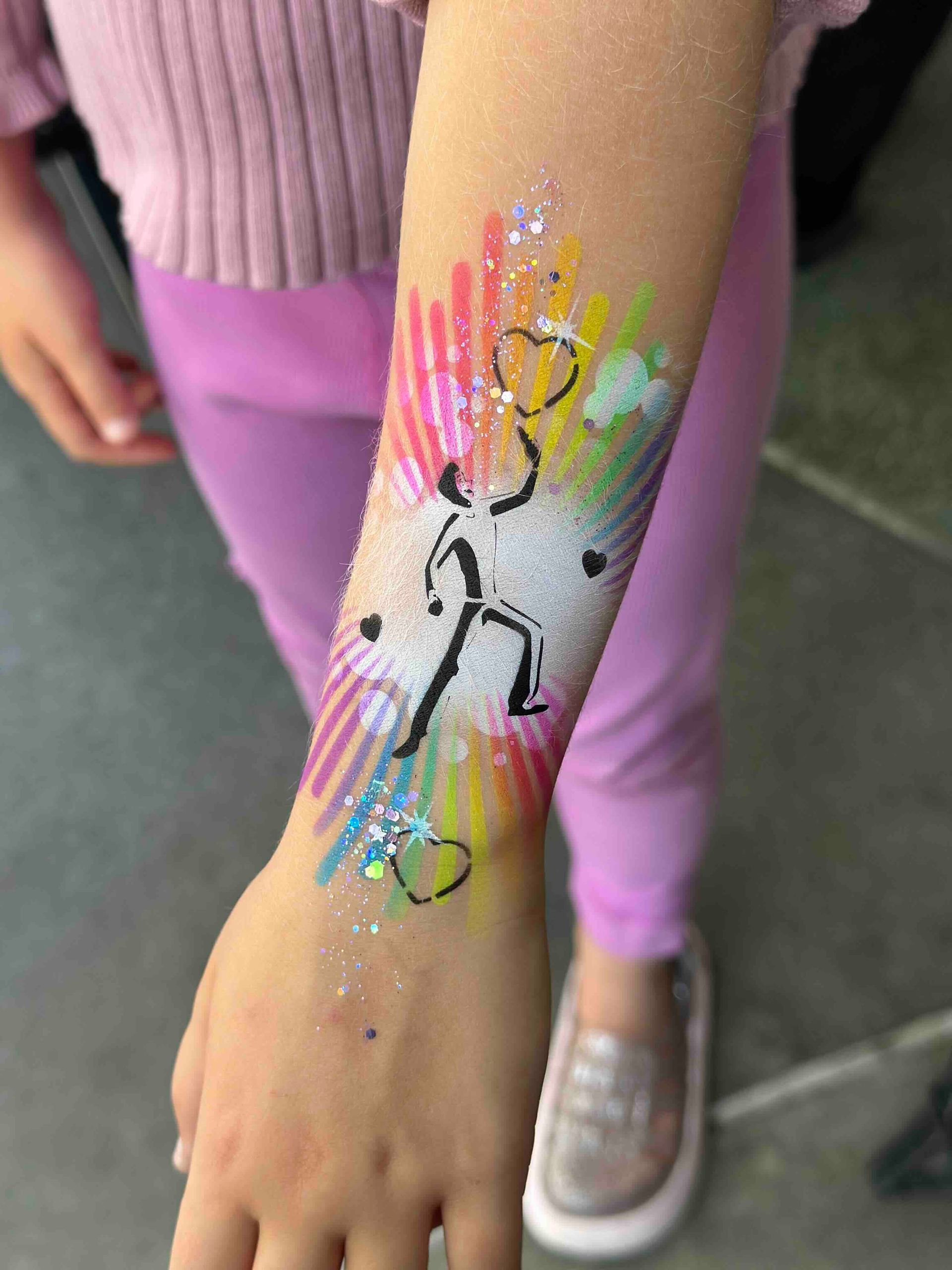 A little girl has a colorful tattoo on her arm.