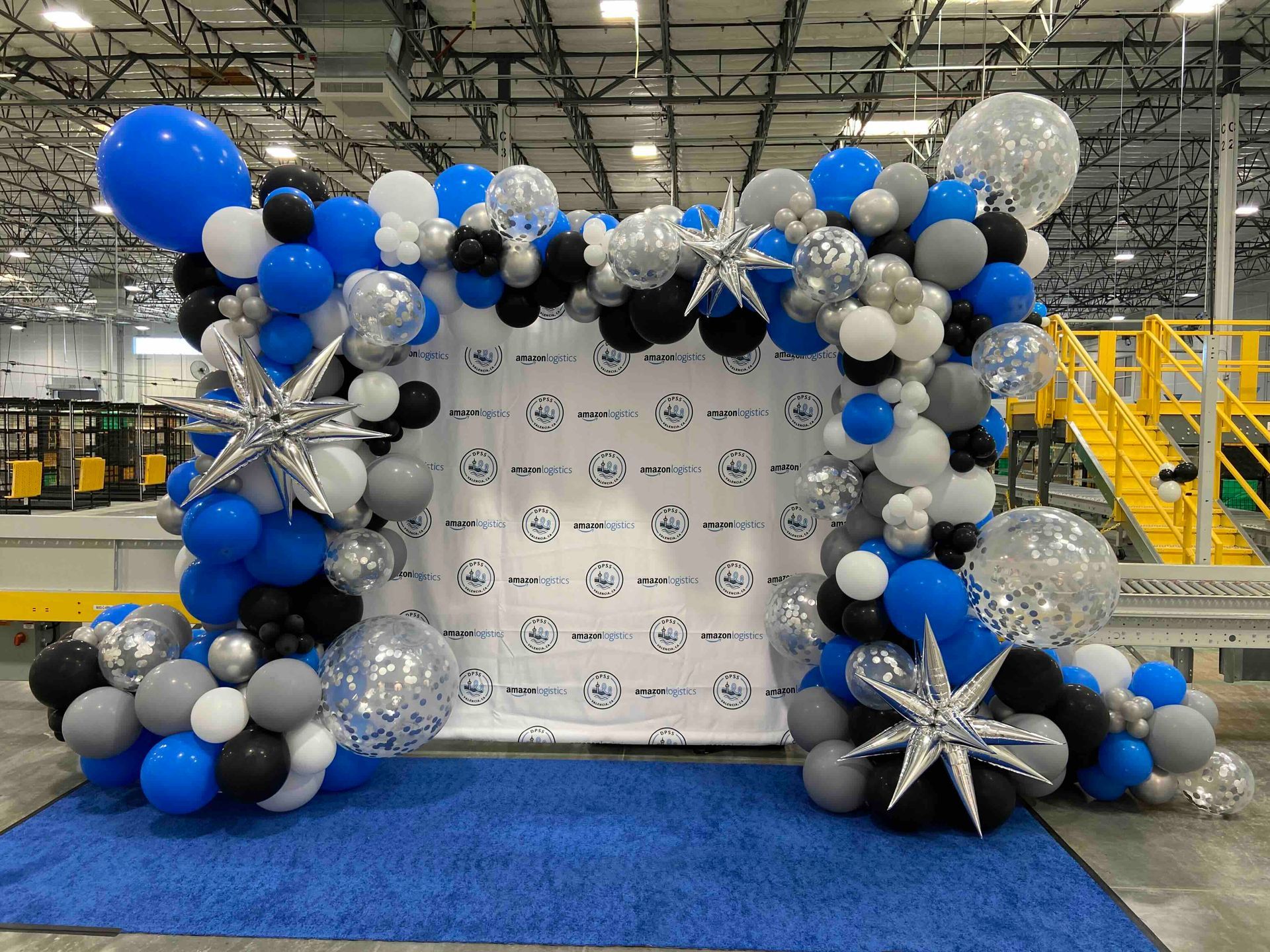 A bunch of balloons are sitting on top of a blue rug in a room.