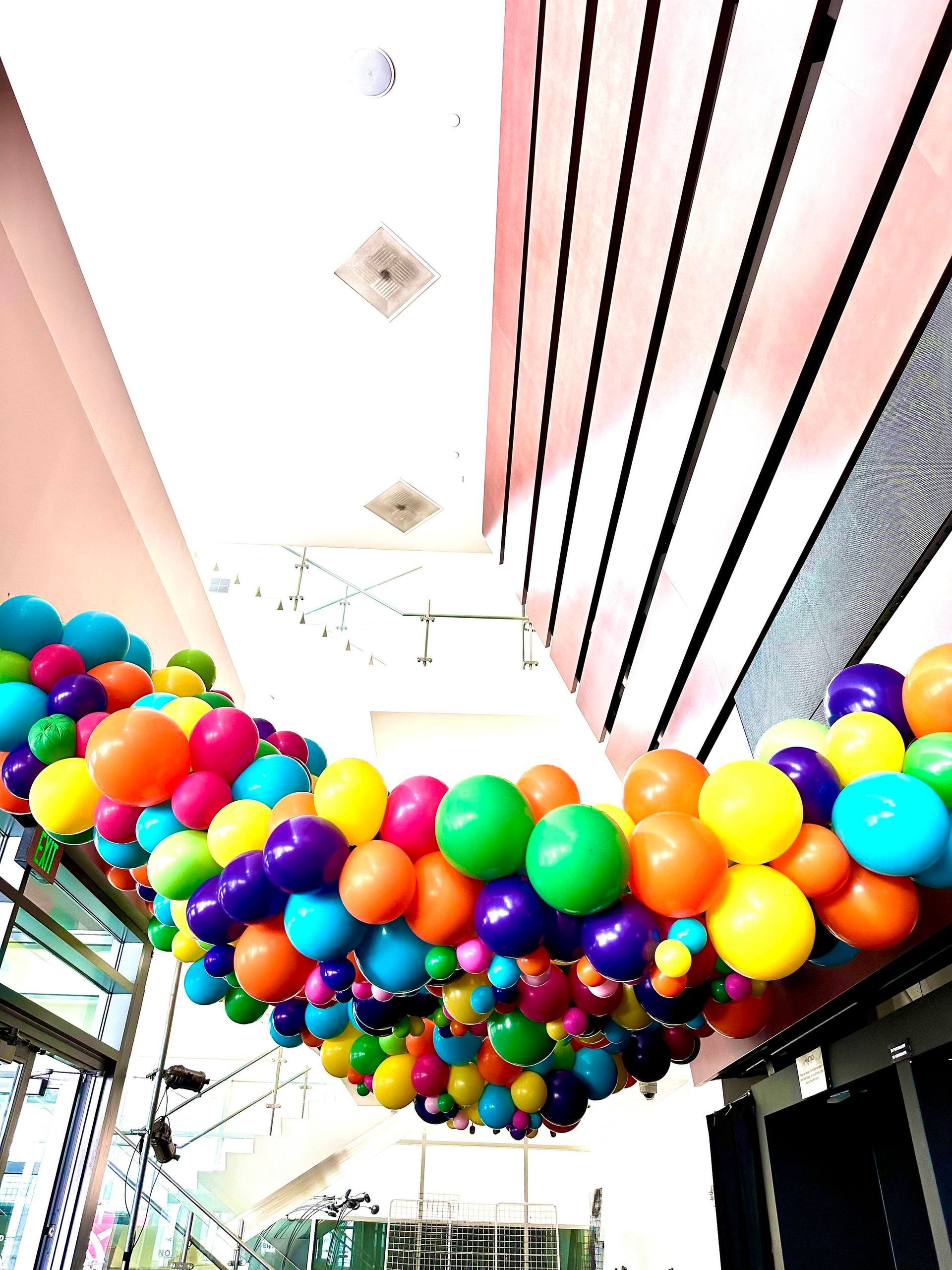 A bunch of colorful balloons are hanging from the ceiling