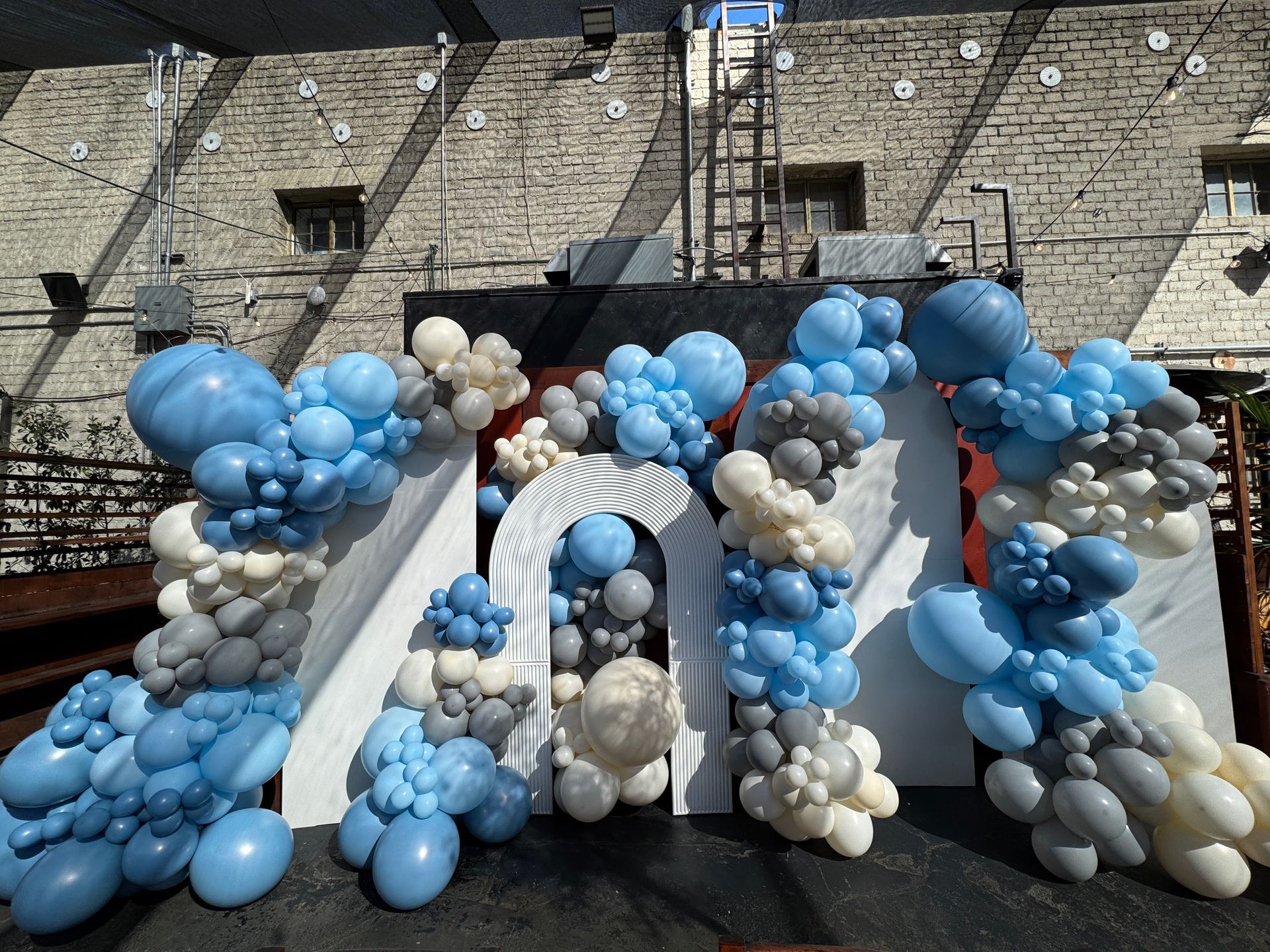 A bunch of blue and white balloons in front of a brick wall
