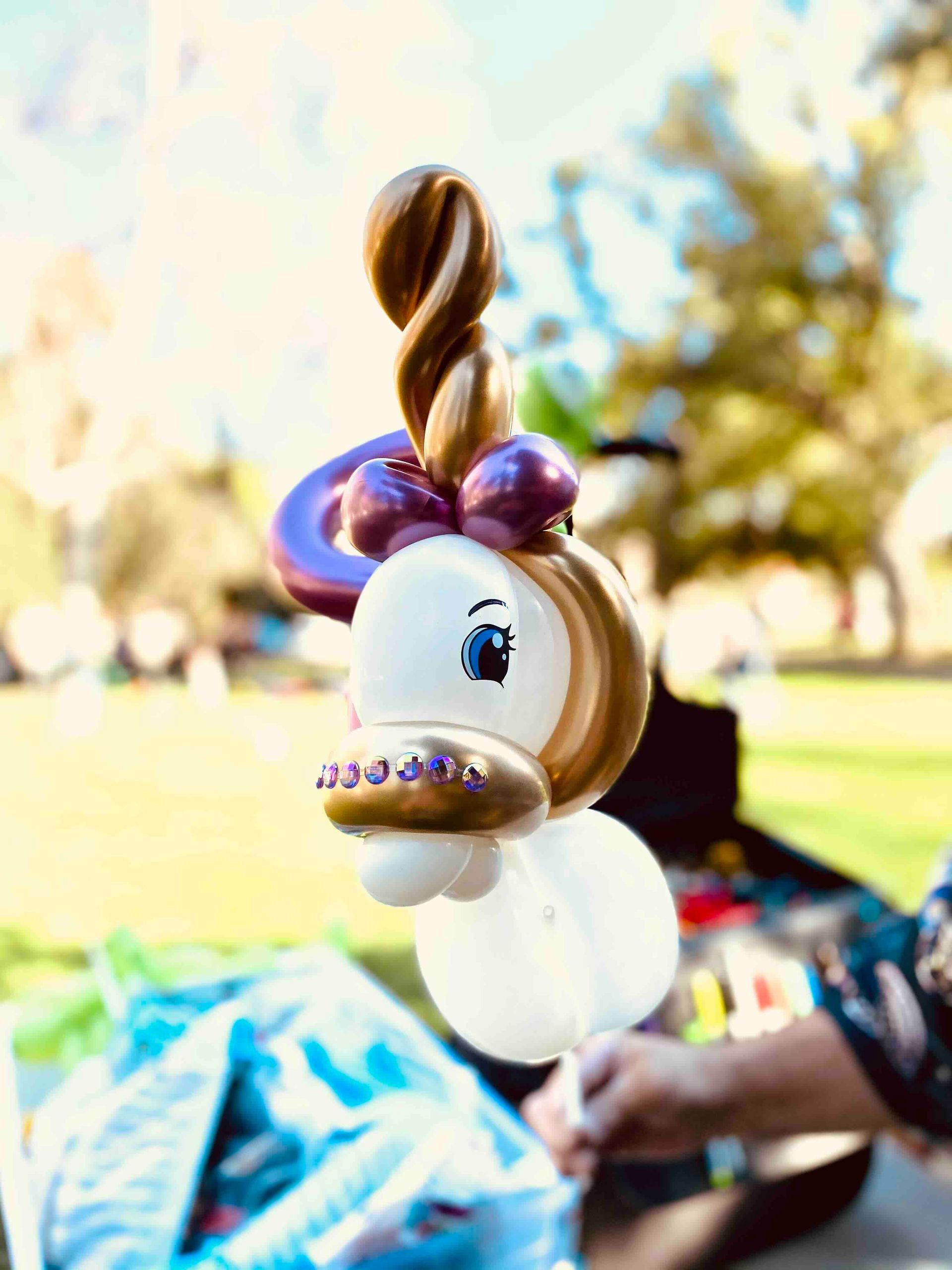 A person is making a balloon unicorn in a park.