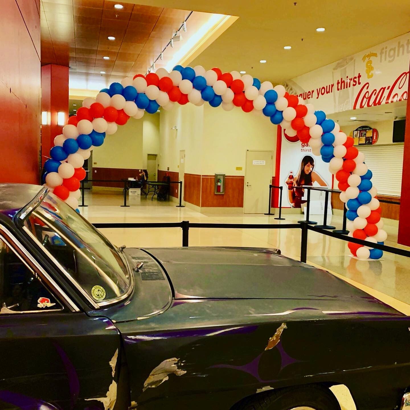 A car is parked under a red white and blue balloon arch
