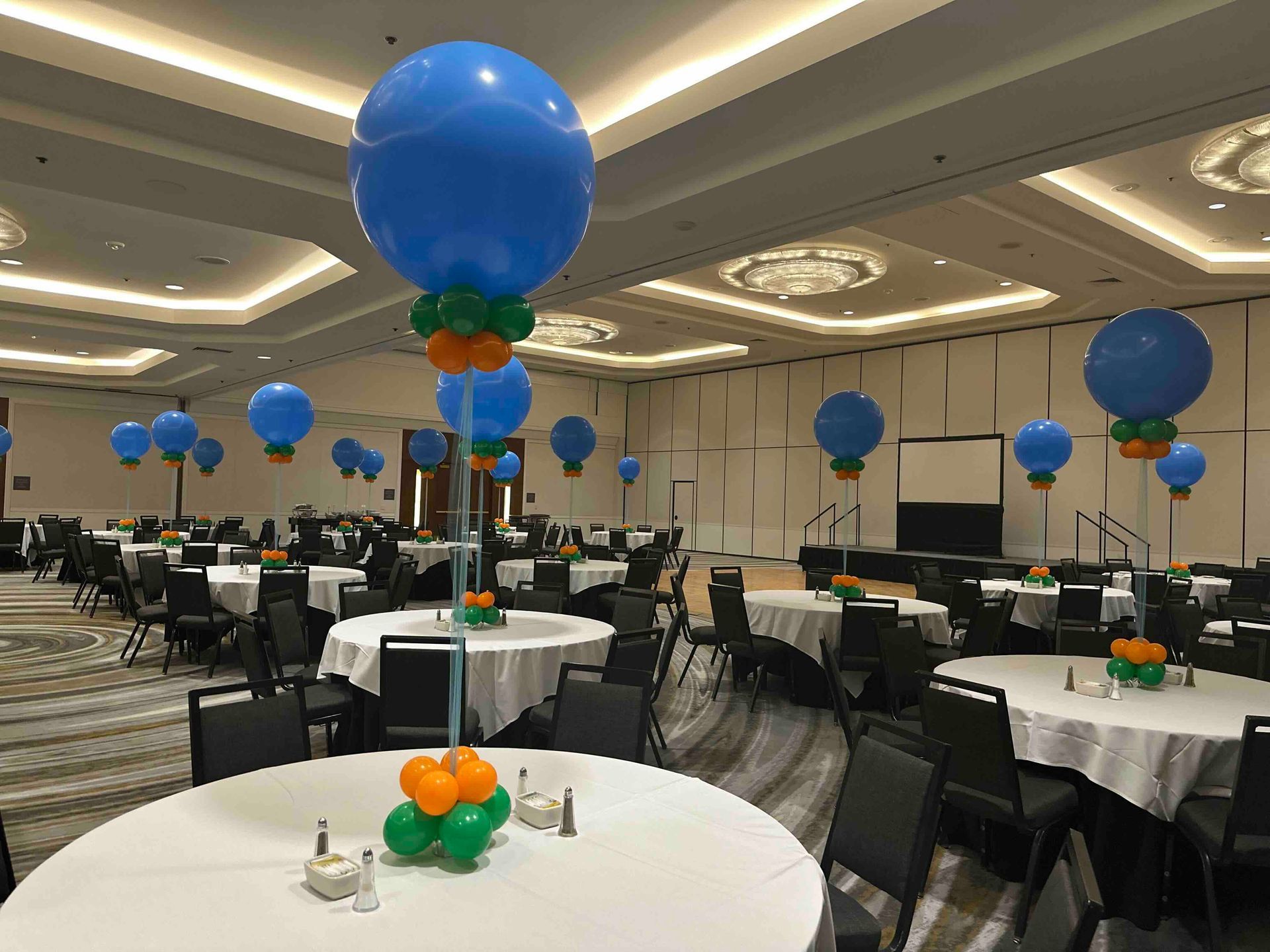 A large room filled with tables and chairs decorated with balloons.