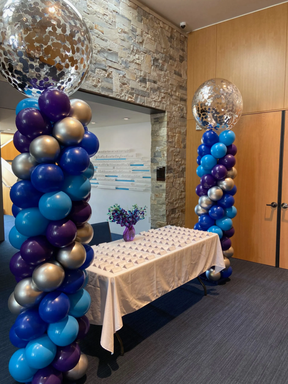 Two columns of blue and purple balloons are surrounding a table