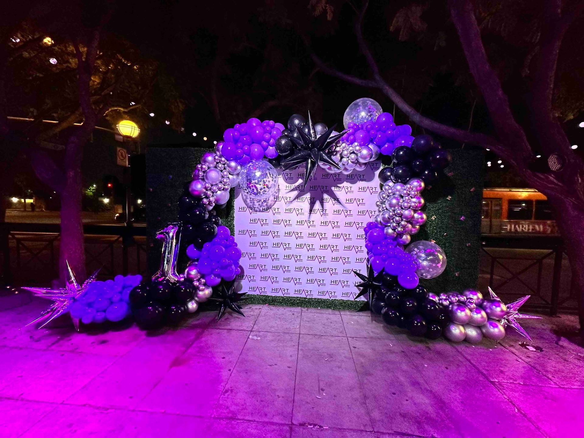 A wall covered in balloons and purple lights at night club event.