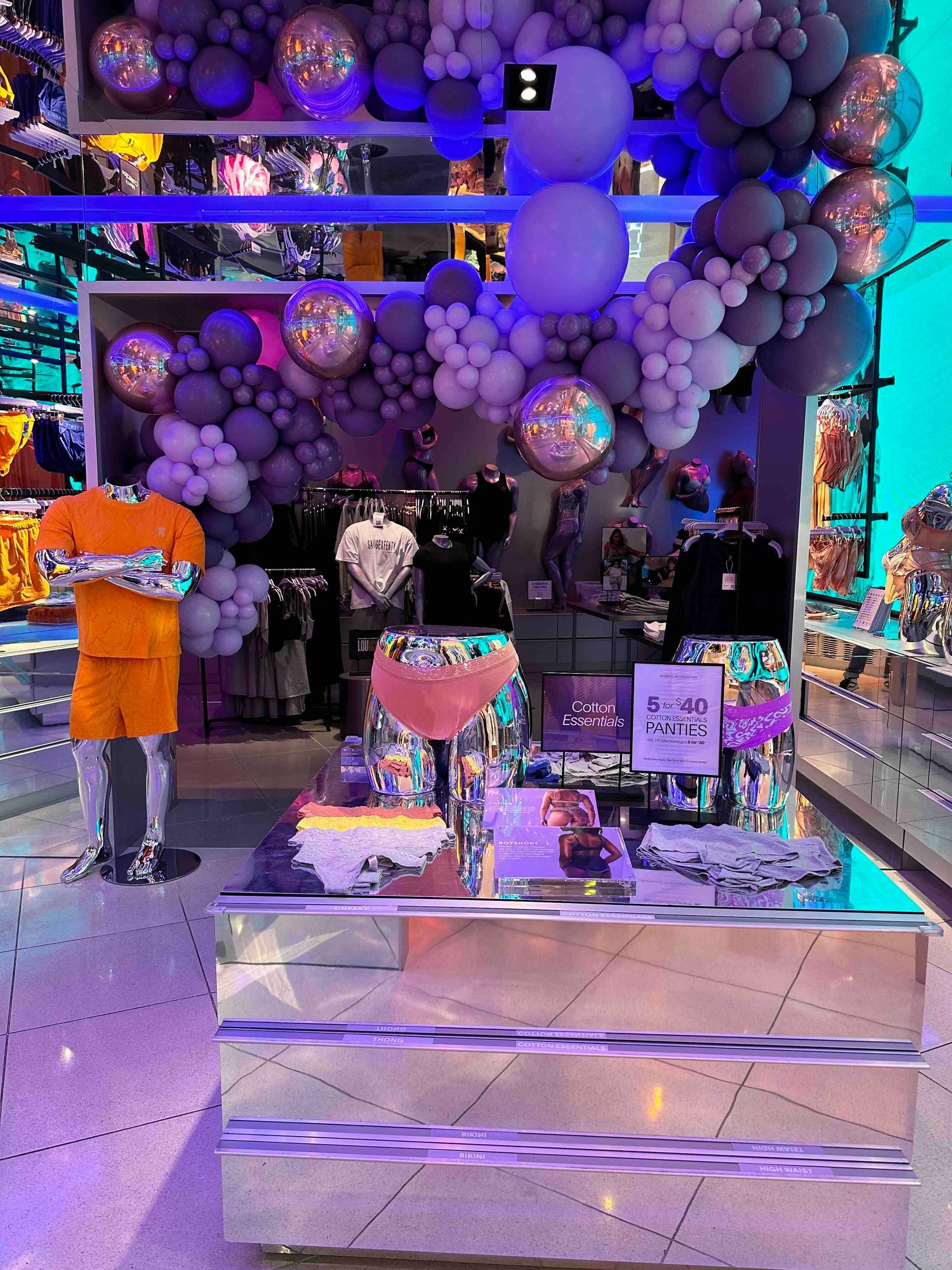 A store with balloons hanging from the ceiling and a table with balloons on it.