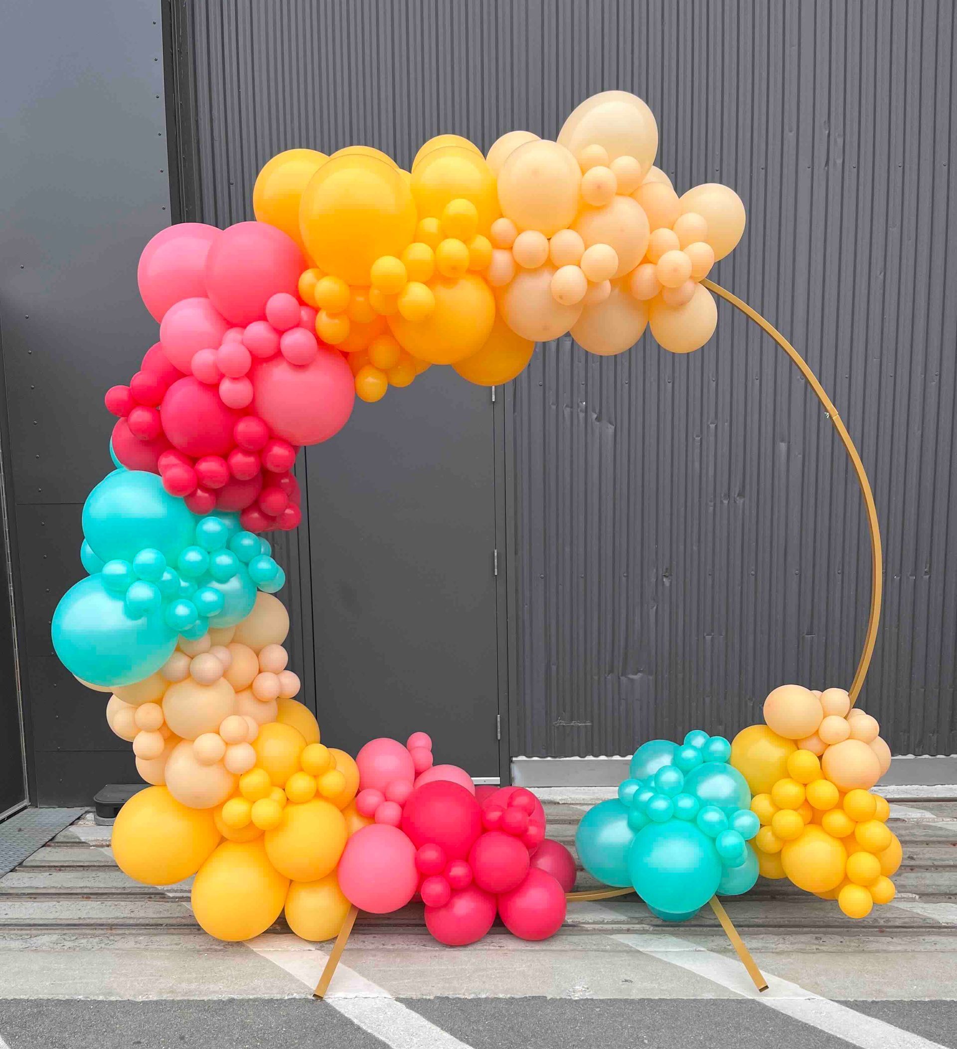 A bunch of colorful balloons are sitting on the ground in front of a building.