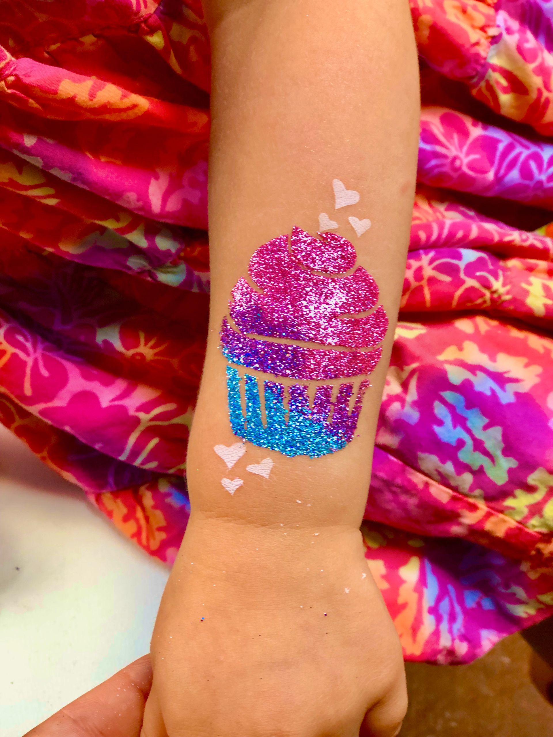 A little girl has a cupcake tattoo on her arm