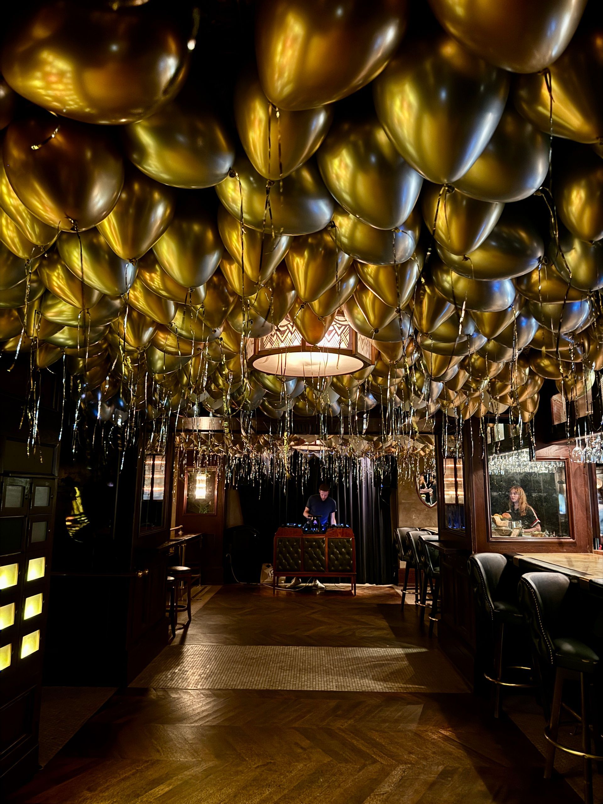 A restaurant with a lot of gold balloons hanging from the ceiling