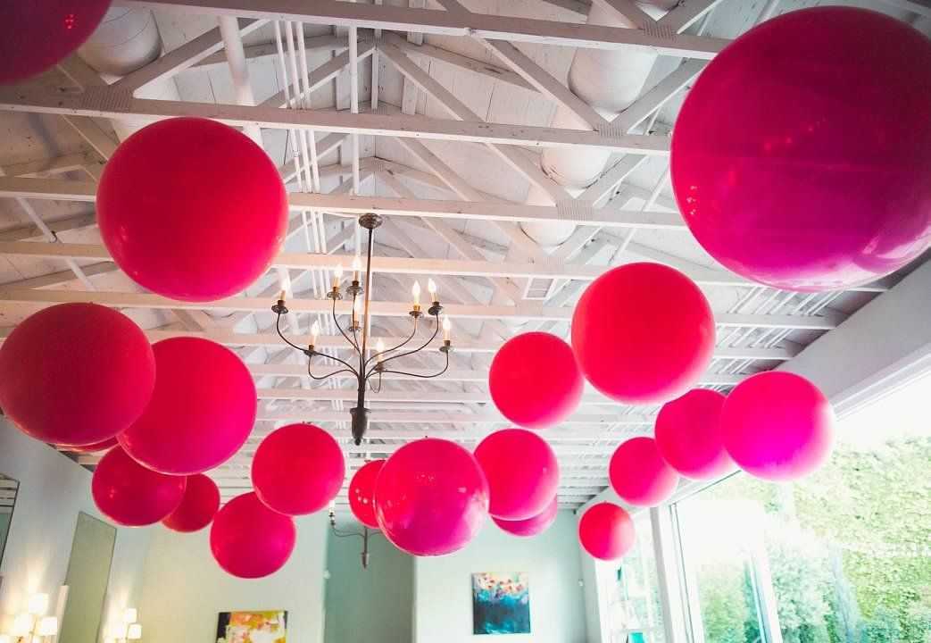 A bunch of pink balloons are hanging from the ceiling