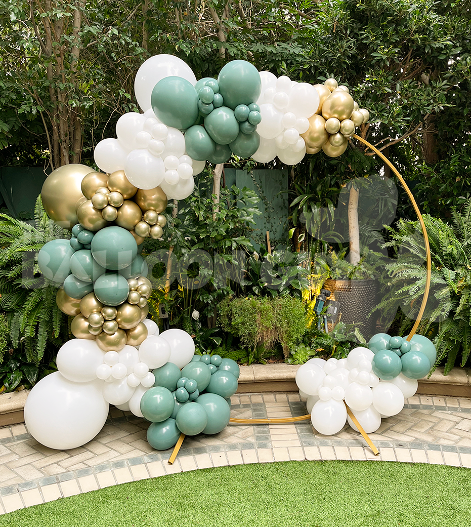 A balloon arch is sitting on top of a lush green field.