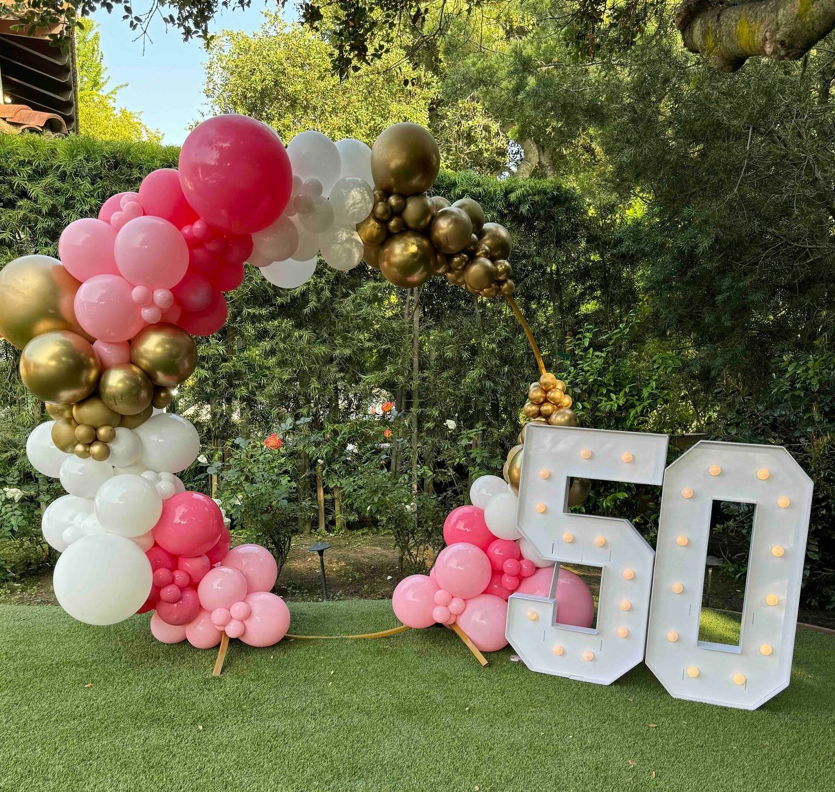 A sign that says 50 is surrounded by balloons and lights.
