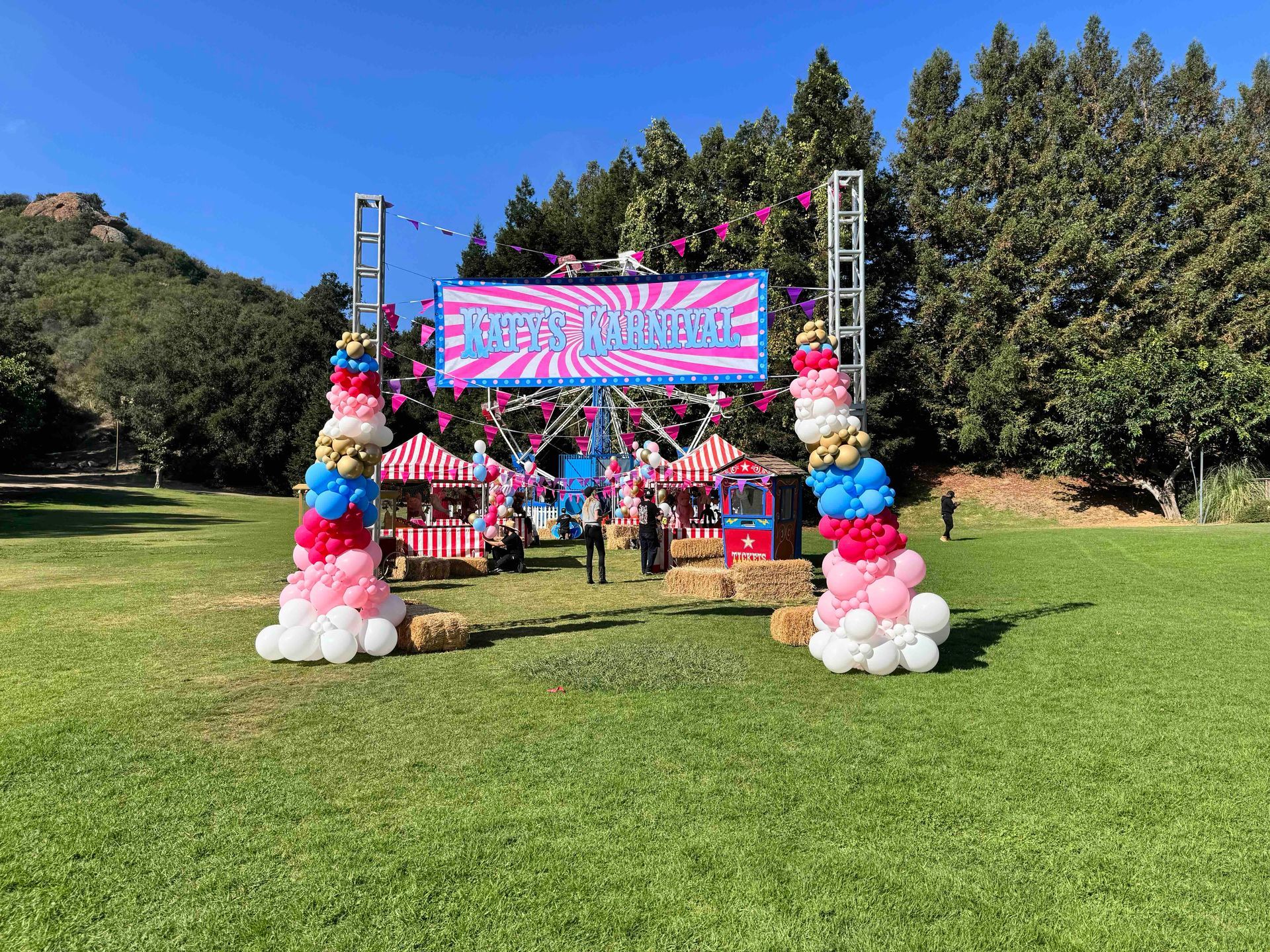 A ferris wheel is decorated with balloons and popcorn in a park.