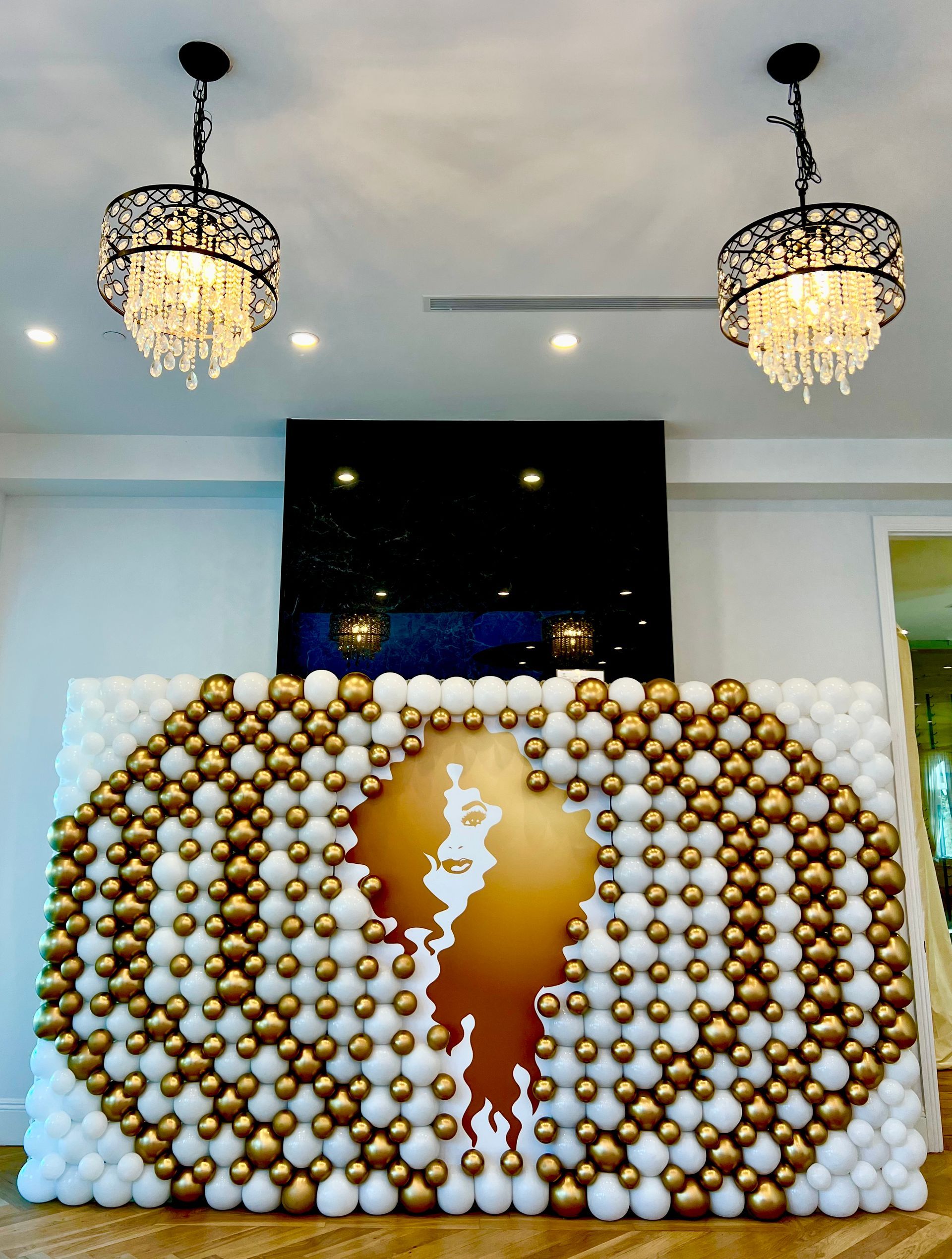 A wall made of white and gold balloons in a room