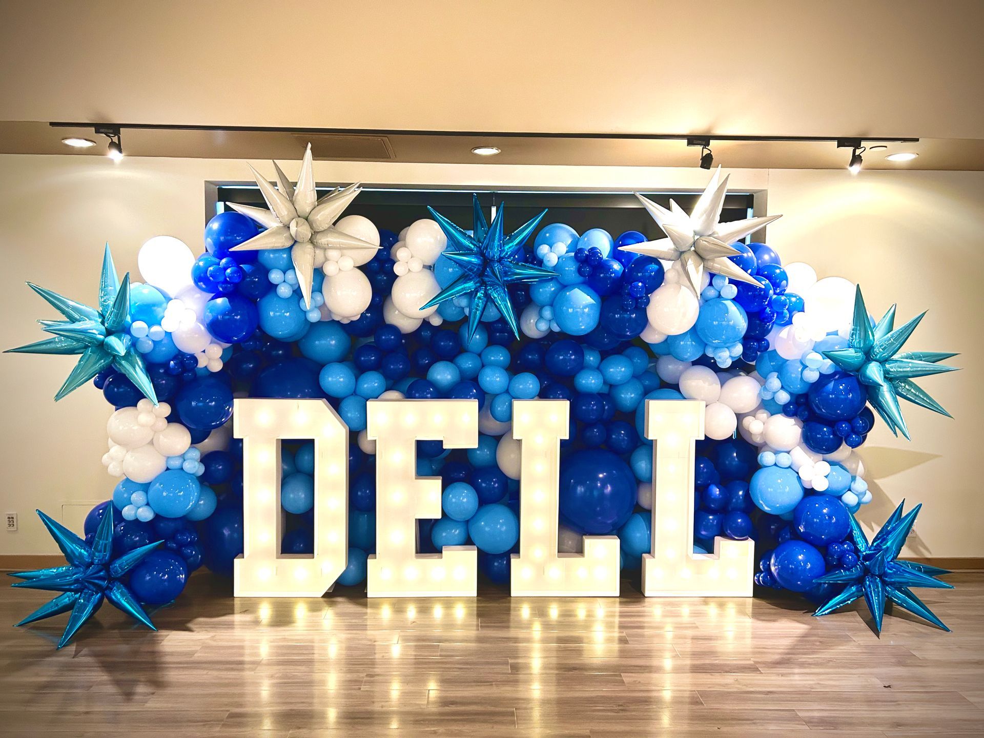 The word dell is surrounded by blue and white balloons and stars.