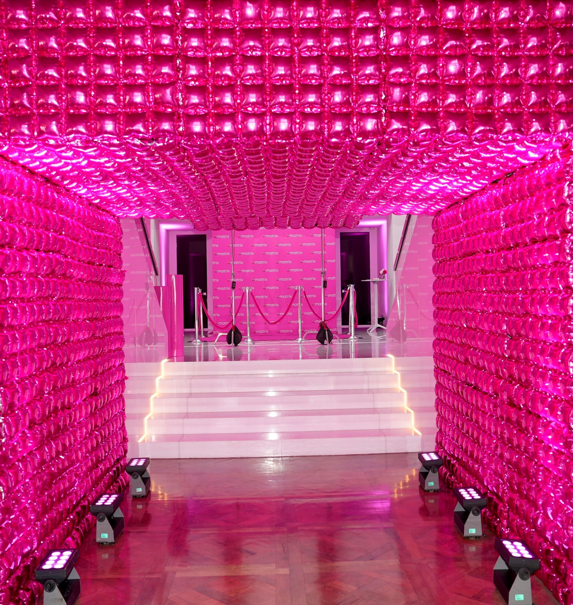 A hallway with pink walls and stairs leading to a stage