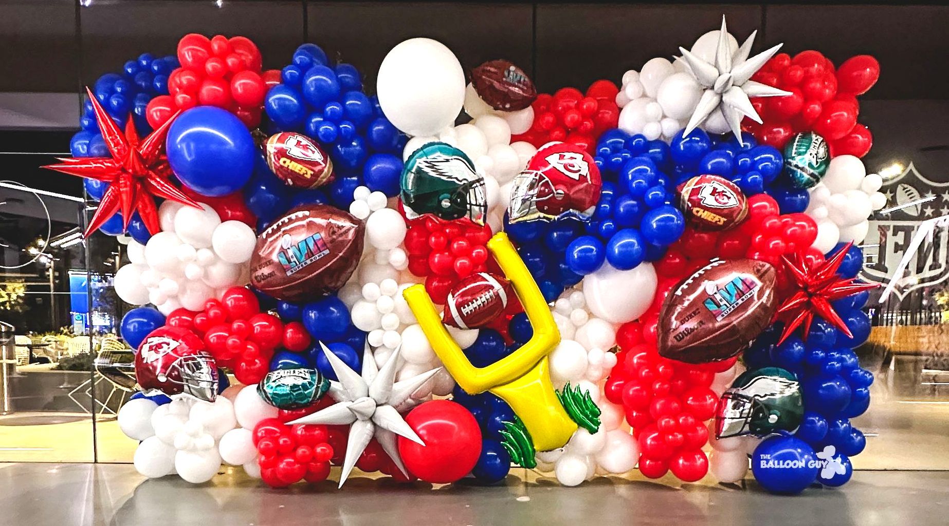 A wall filled with red , white , and blue balloons.