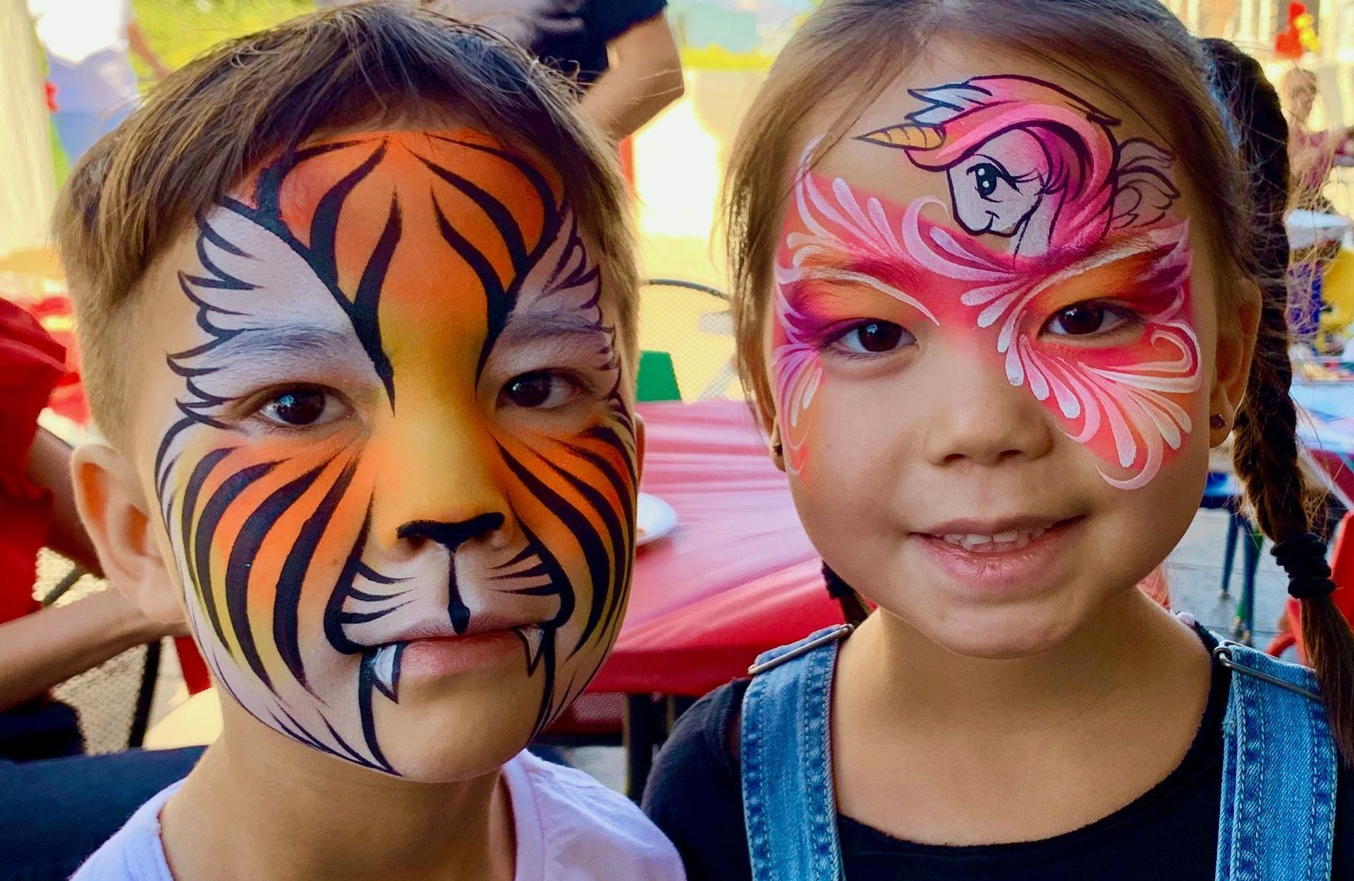 A boy and a girl with their faces painted like tigers.